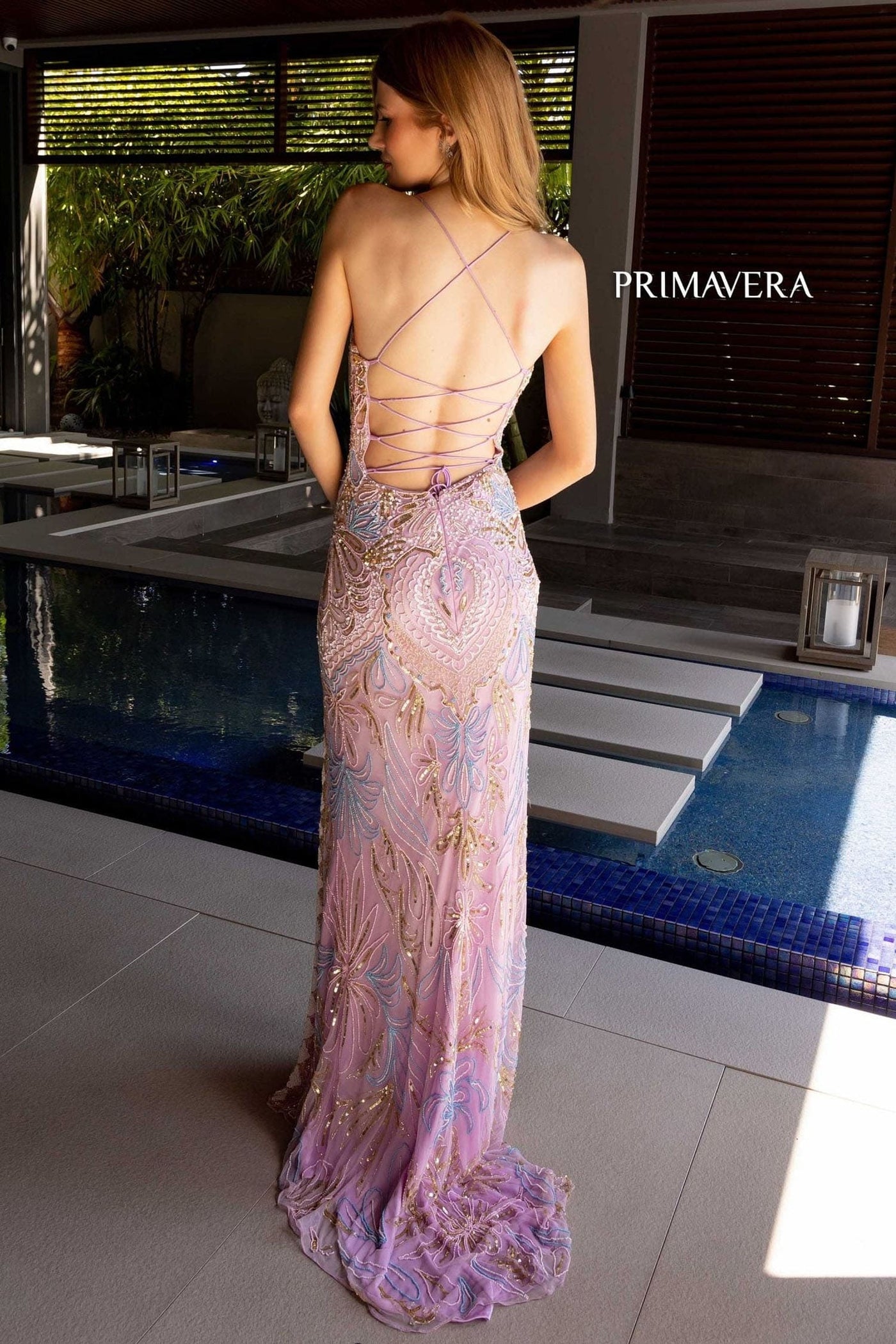 Woman in a floral evening gown by Primavera standing by a pool.