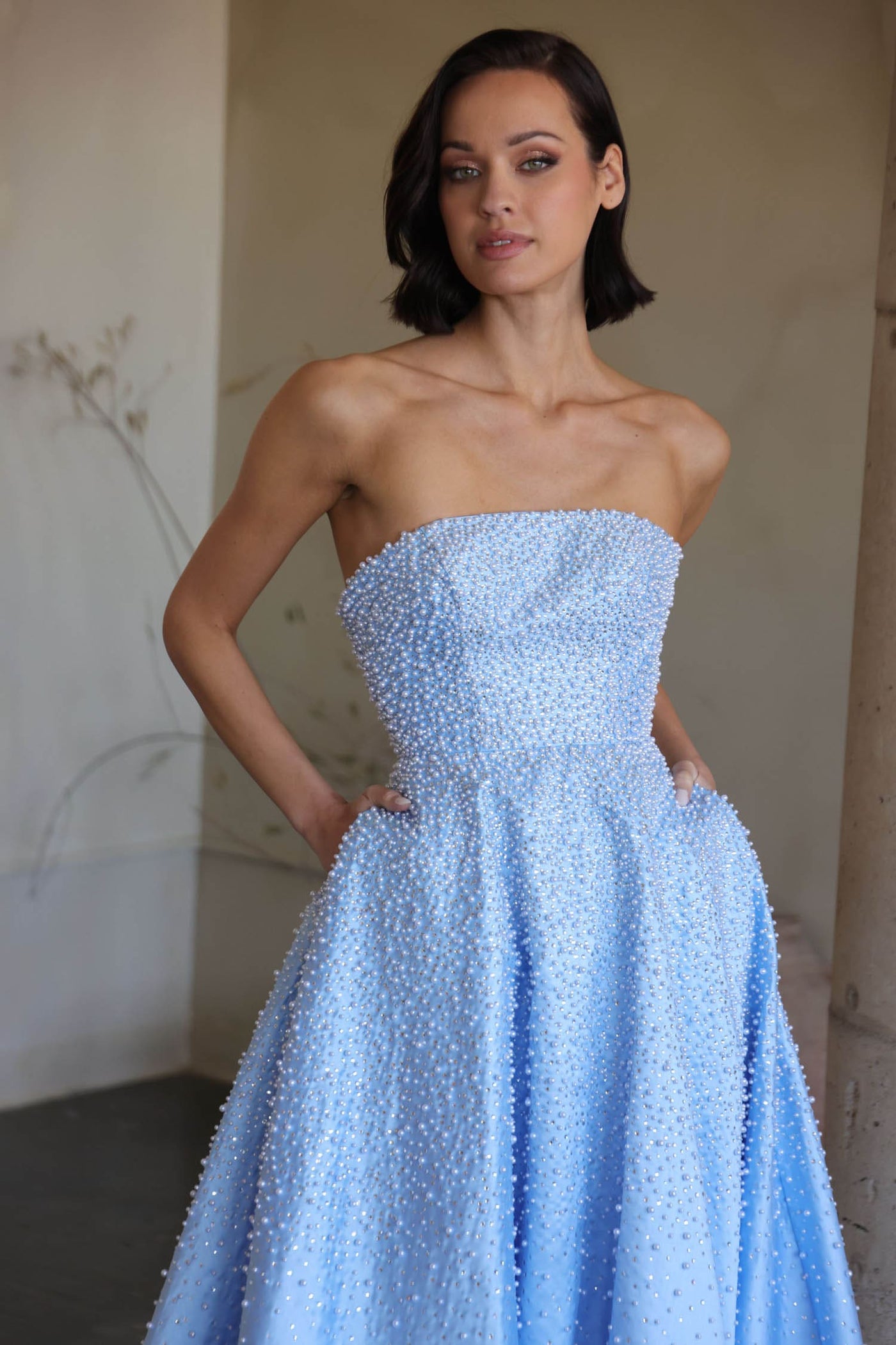 Woman wearing a light blue strapless gown against a neutral background