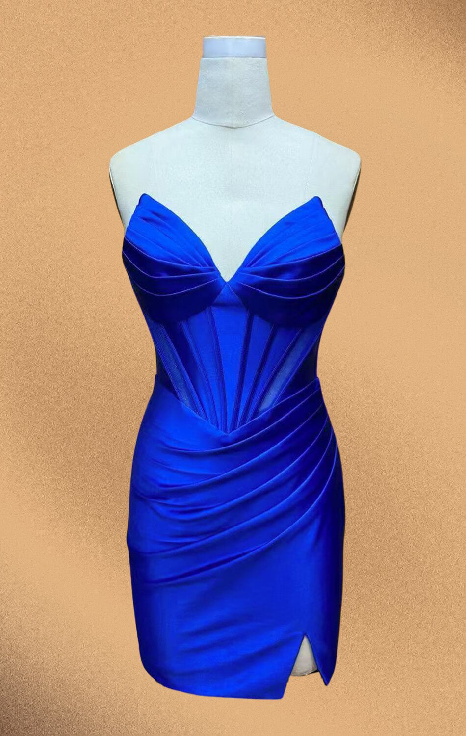 Woman wearing a blue strapless dress standing against a beige wall.