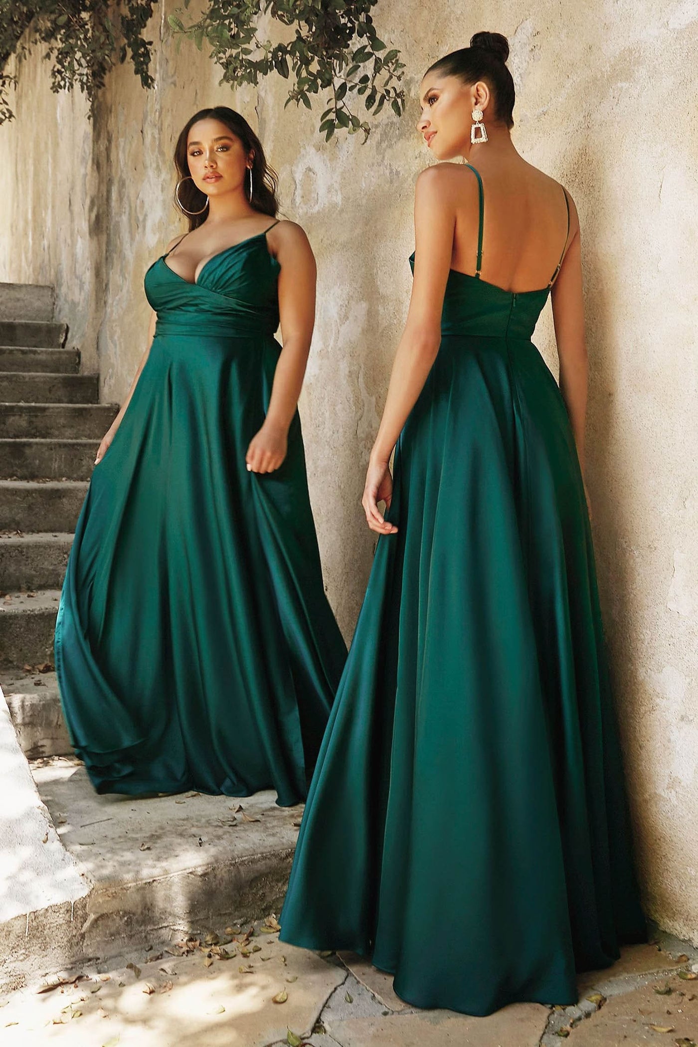 Woman in a green evening gown standing on stone steps with a stone wall background.