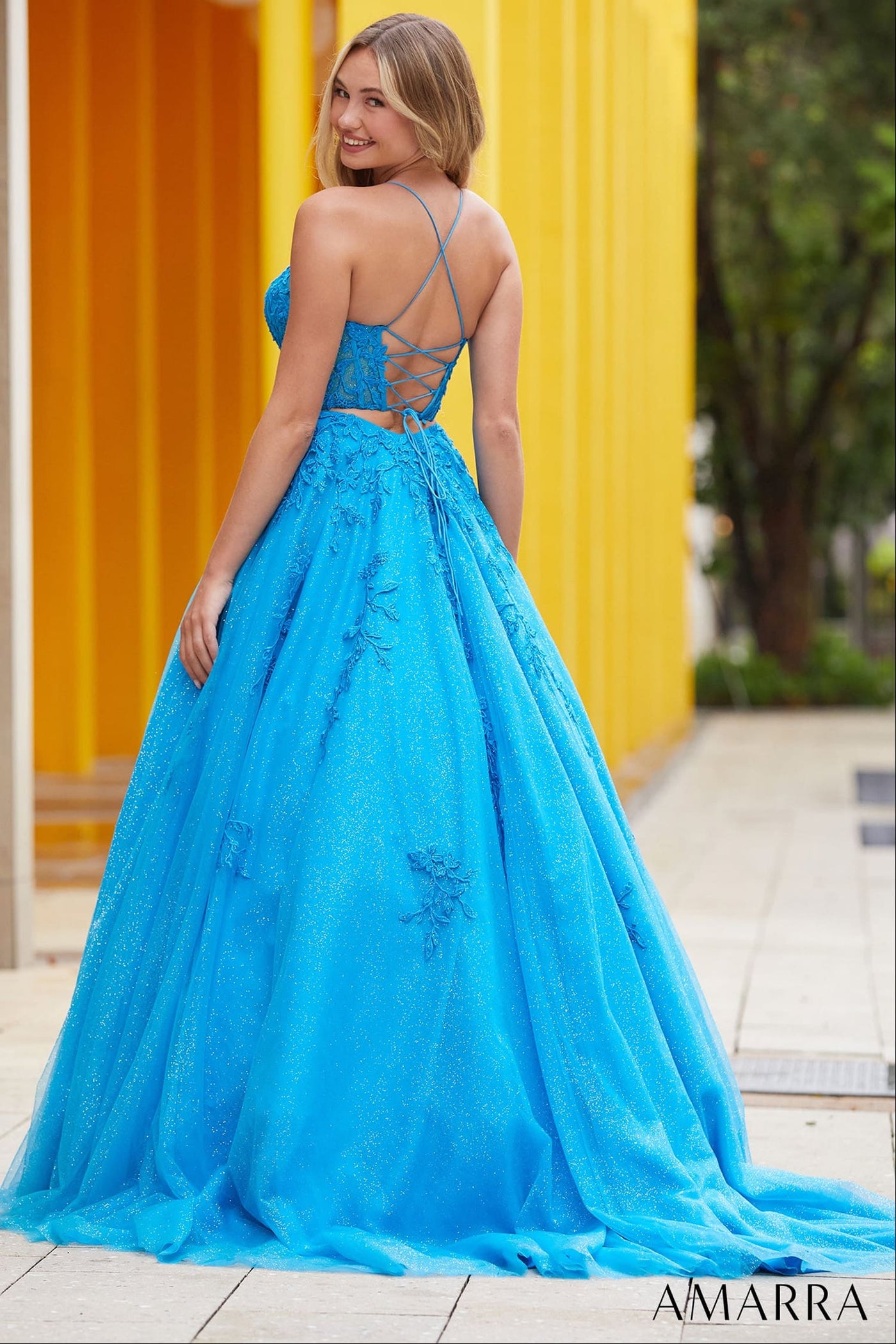 Woman wearing a blue evening gown with a yellow wall in the background