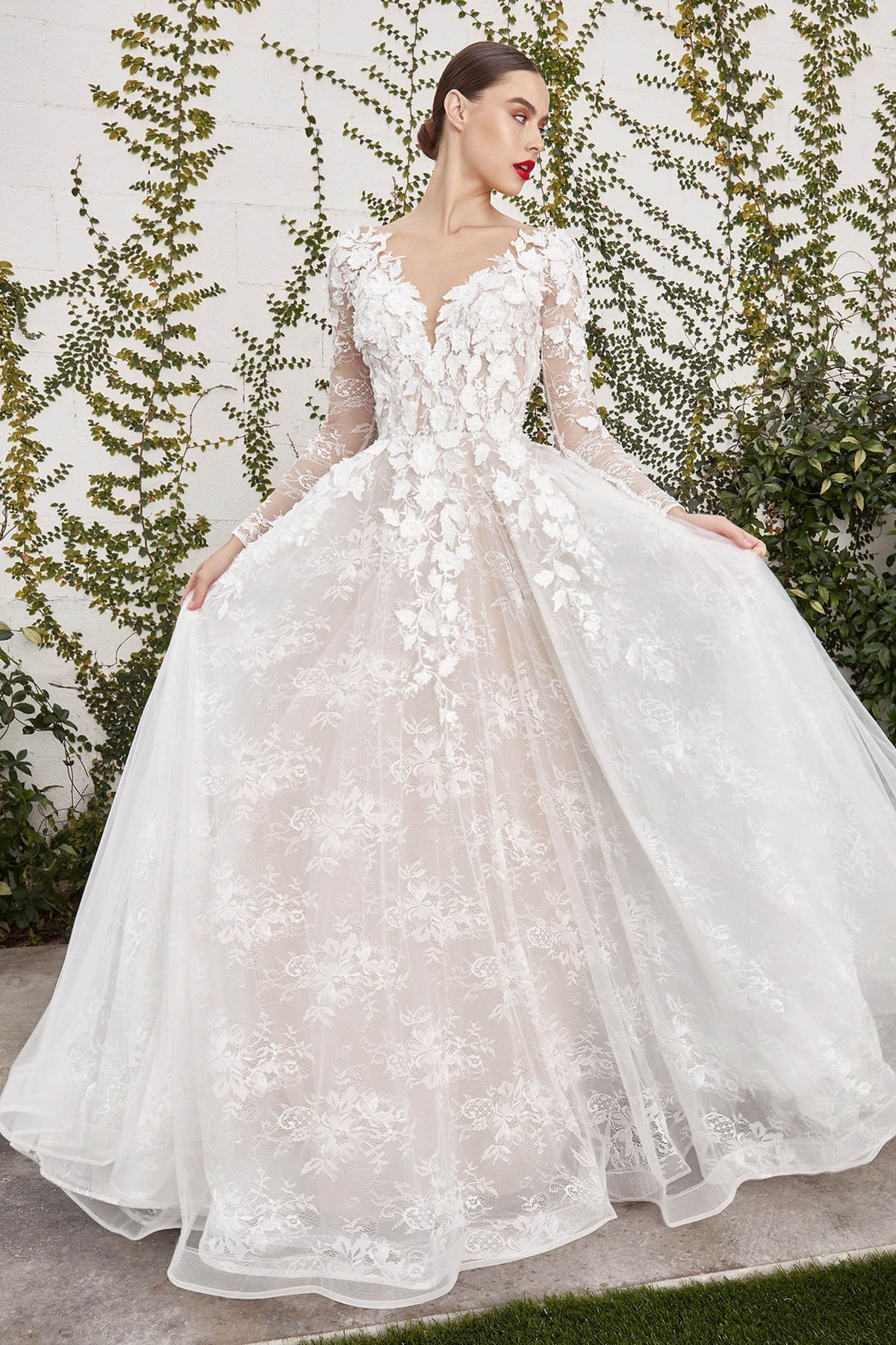 Woman wearing a white floral embroidered wedding dress against a green leafy background