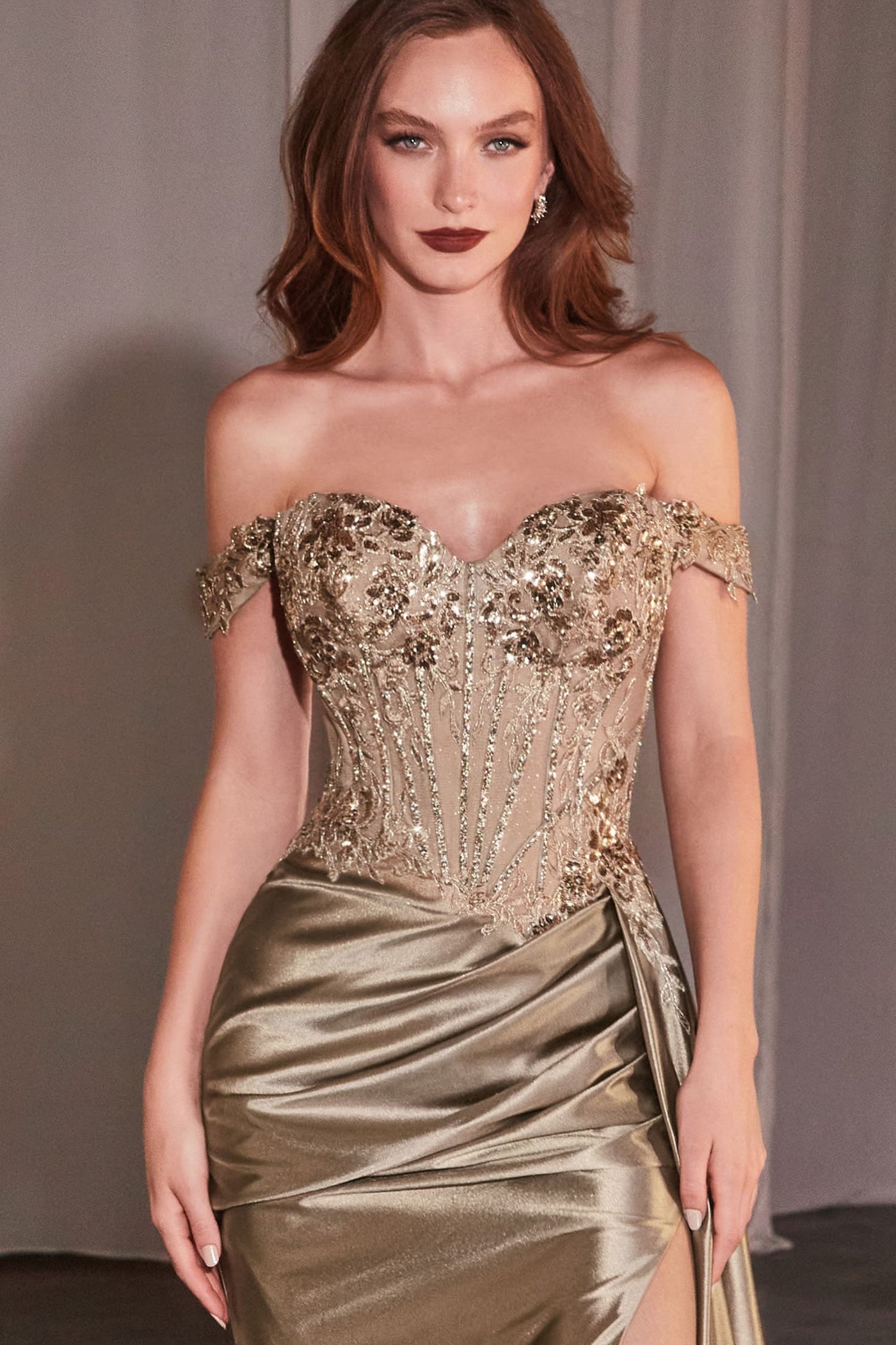Woman wearing a gold off-shoulder evening gown with intricate detailing.