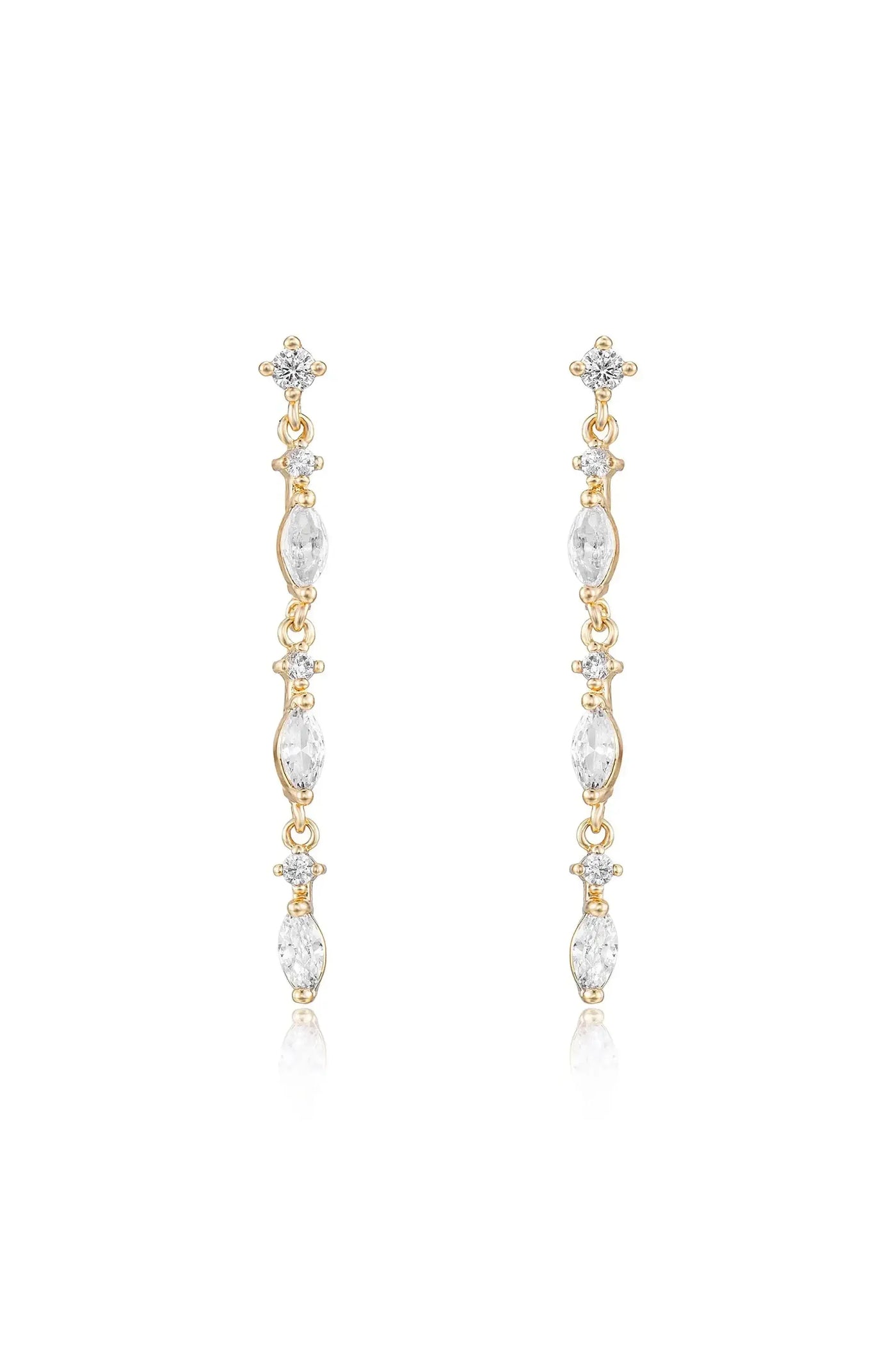 Long, elegant gold earrings feature a series of clear, sparkling gemstones arranged vertically. They hang gracefully, reflecting light, set against a plain, bright background.