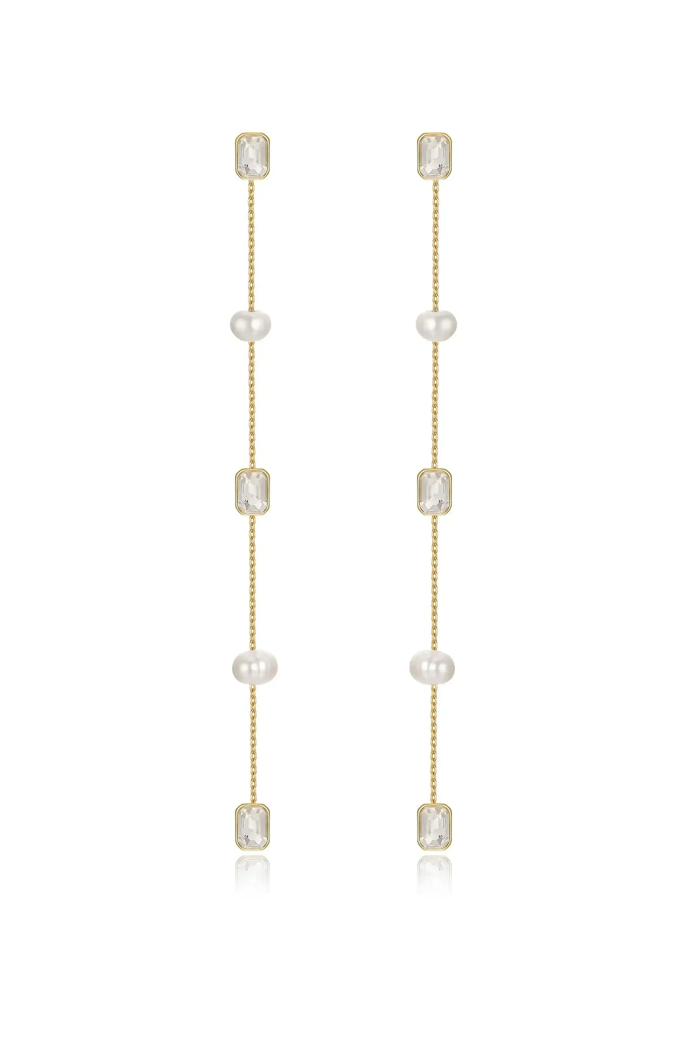 Gold earrings feature four pearl beads and two rectangular clear stones, hanging delicately in a vertical arrangement, reflecting light against a neutral backdrop.