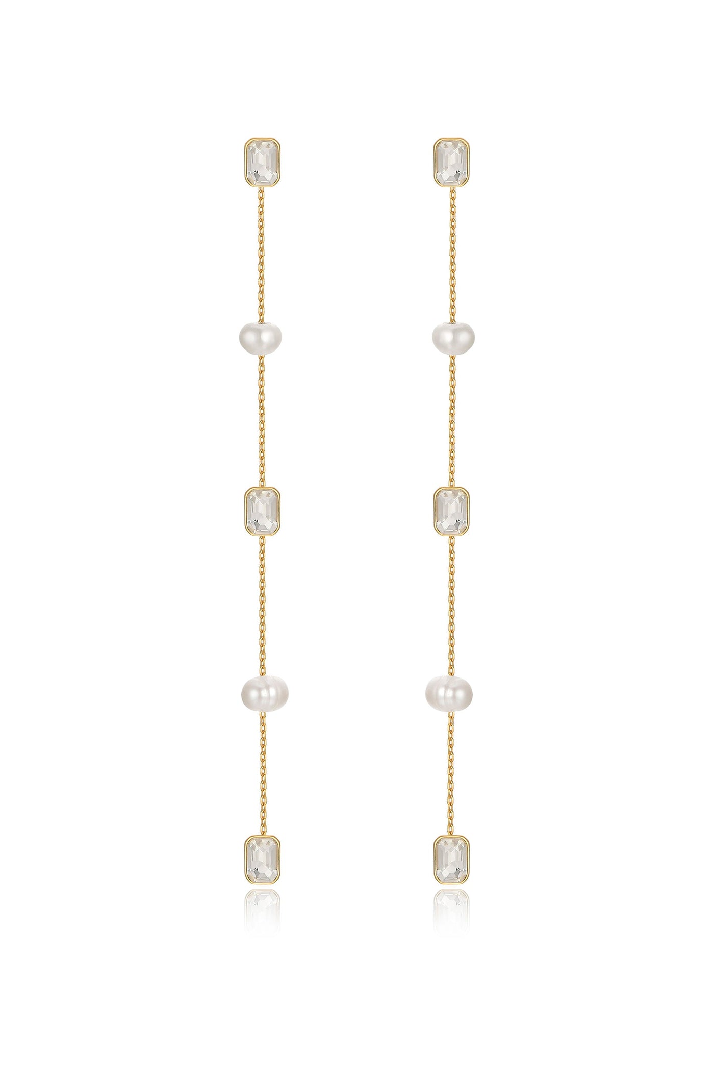 Gold earrings feature four pearl beads and two rectangular clear stones, hanging delicately in a vertical arrangement, reflecting light against a neutral backdrop.