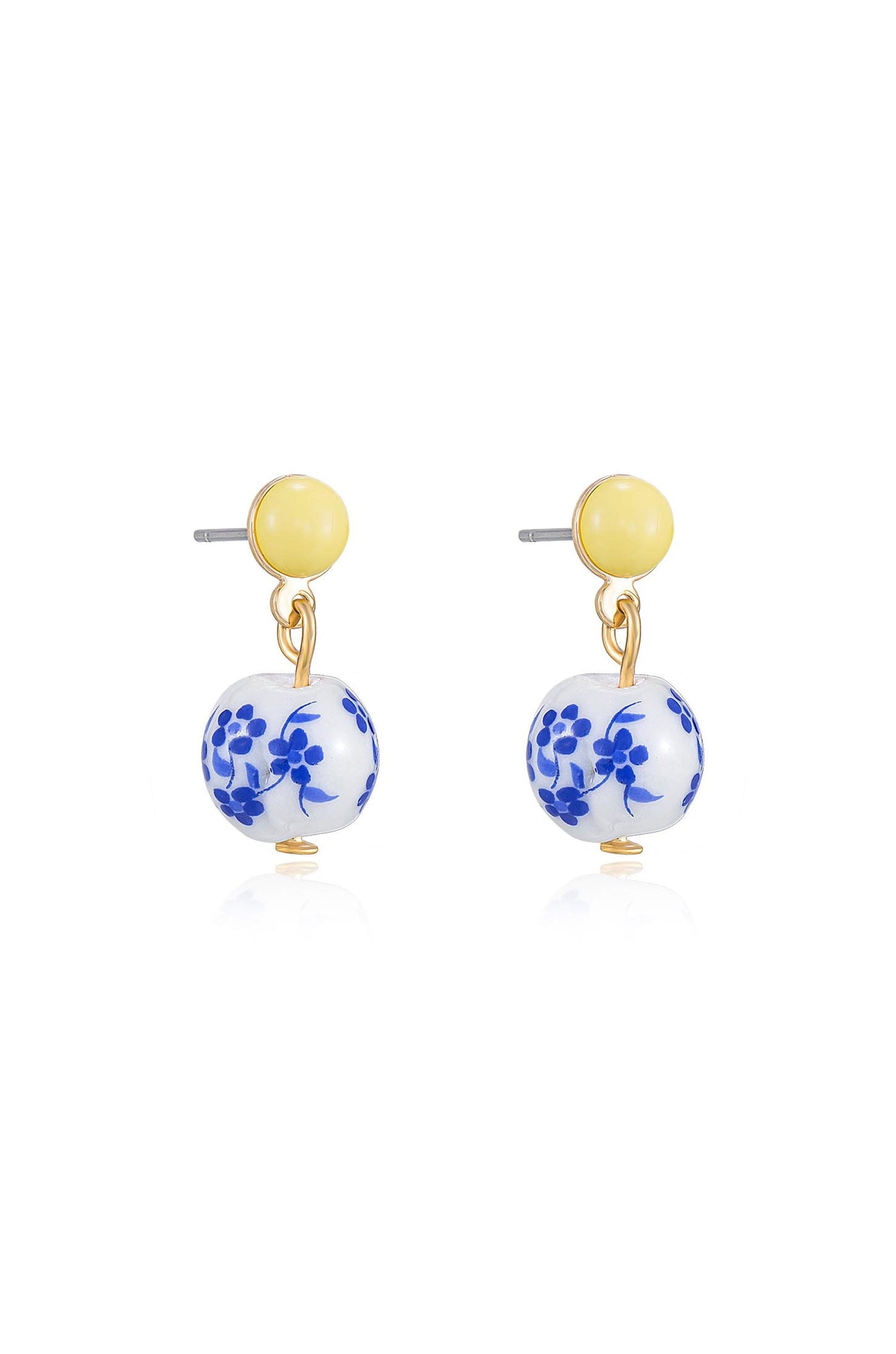 Two earrings are displayed. Each features a yellow circular stud at the top, with a hanging white bead adorned with blue floral patterns below, set against a plain background.
