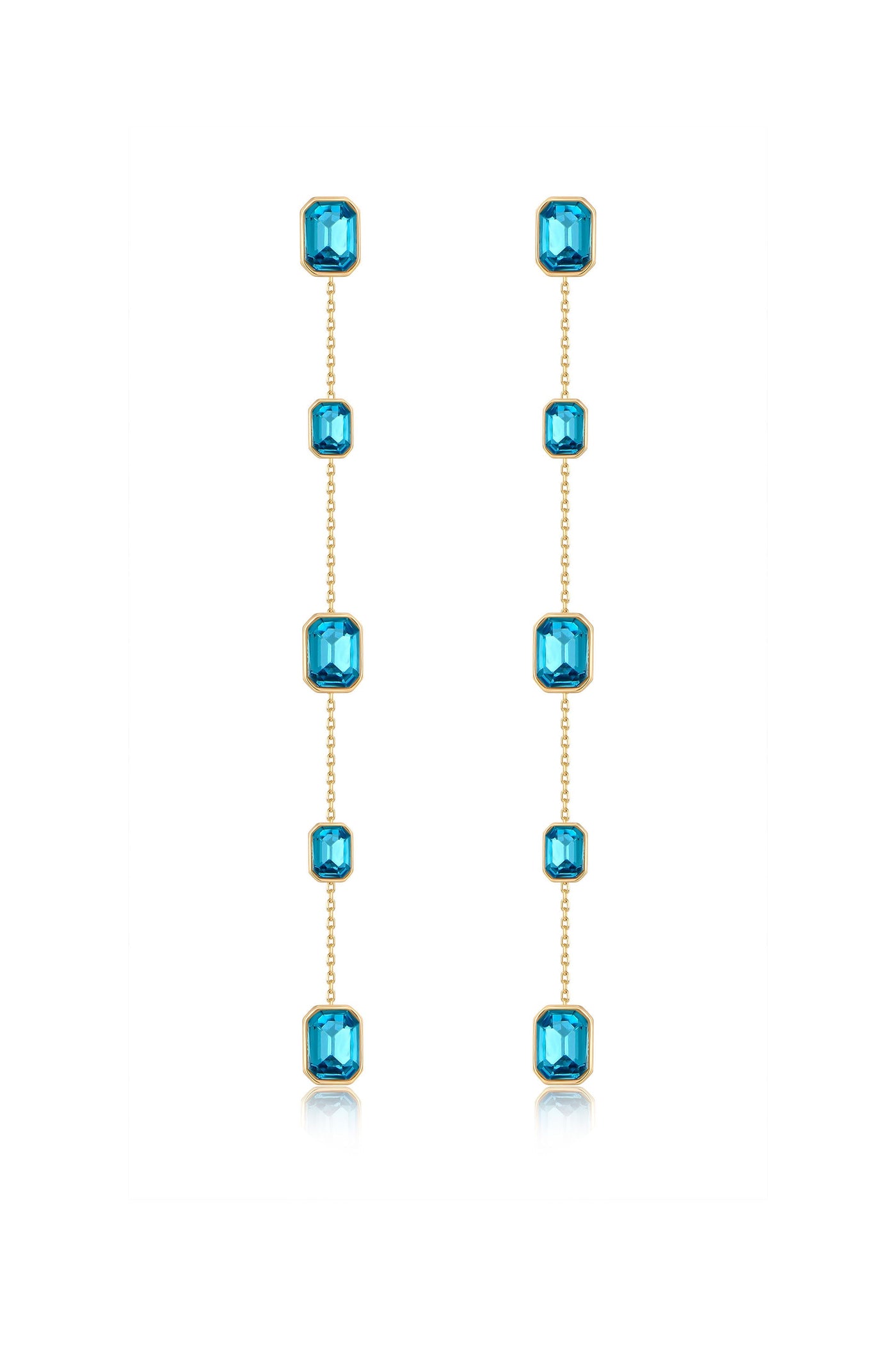 Dangling earrings feature a series of shimmering blue gems set in gold, elegantly hanging down in a vertical arrangement against a white background, highlighting their refined craftsmanship.