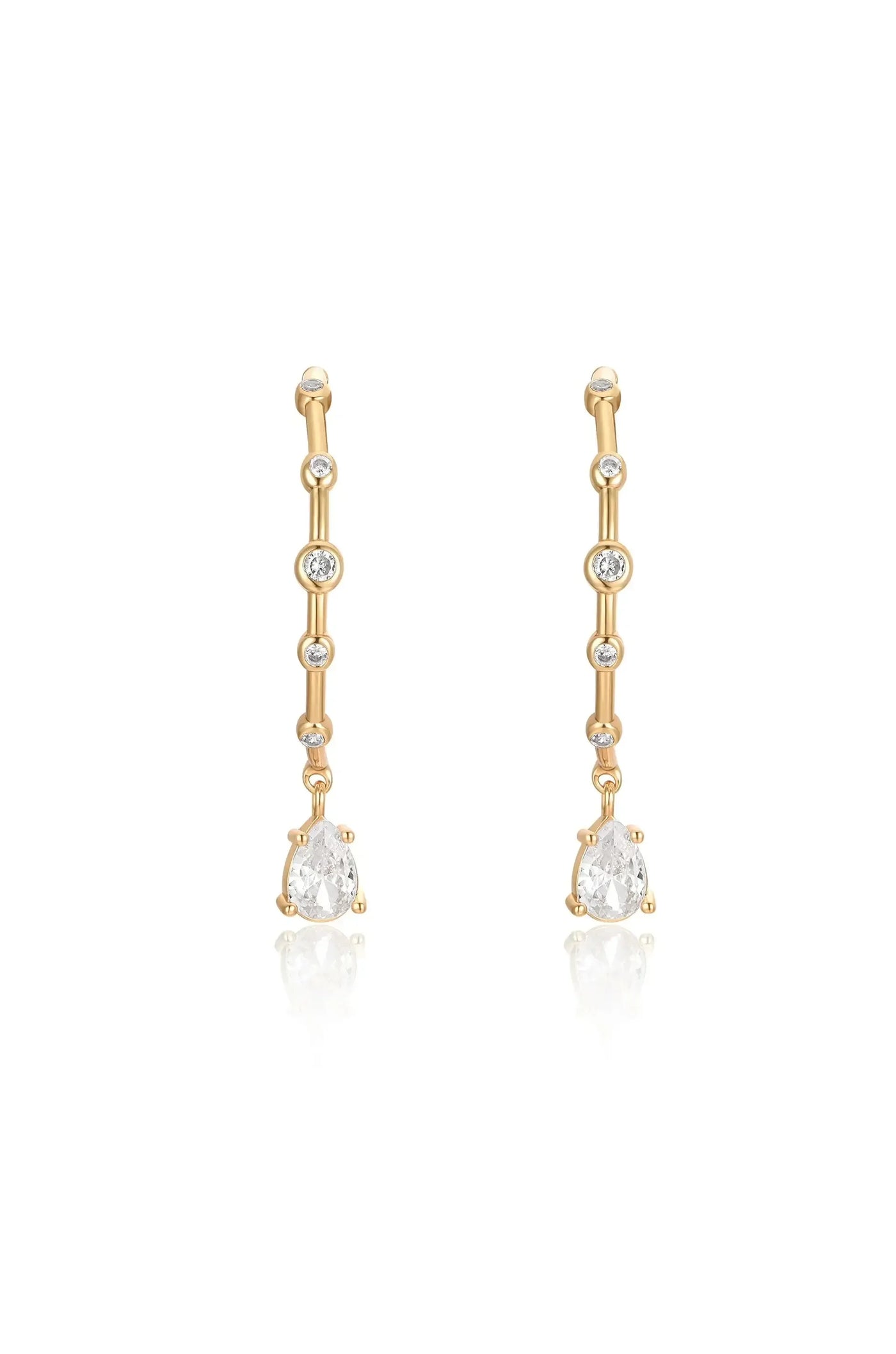Gold drop earrings featuring multiple small diamonds along the length, with a larger pear-shaped diamond dangling at the bottom, set against a reflective surface.