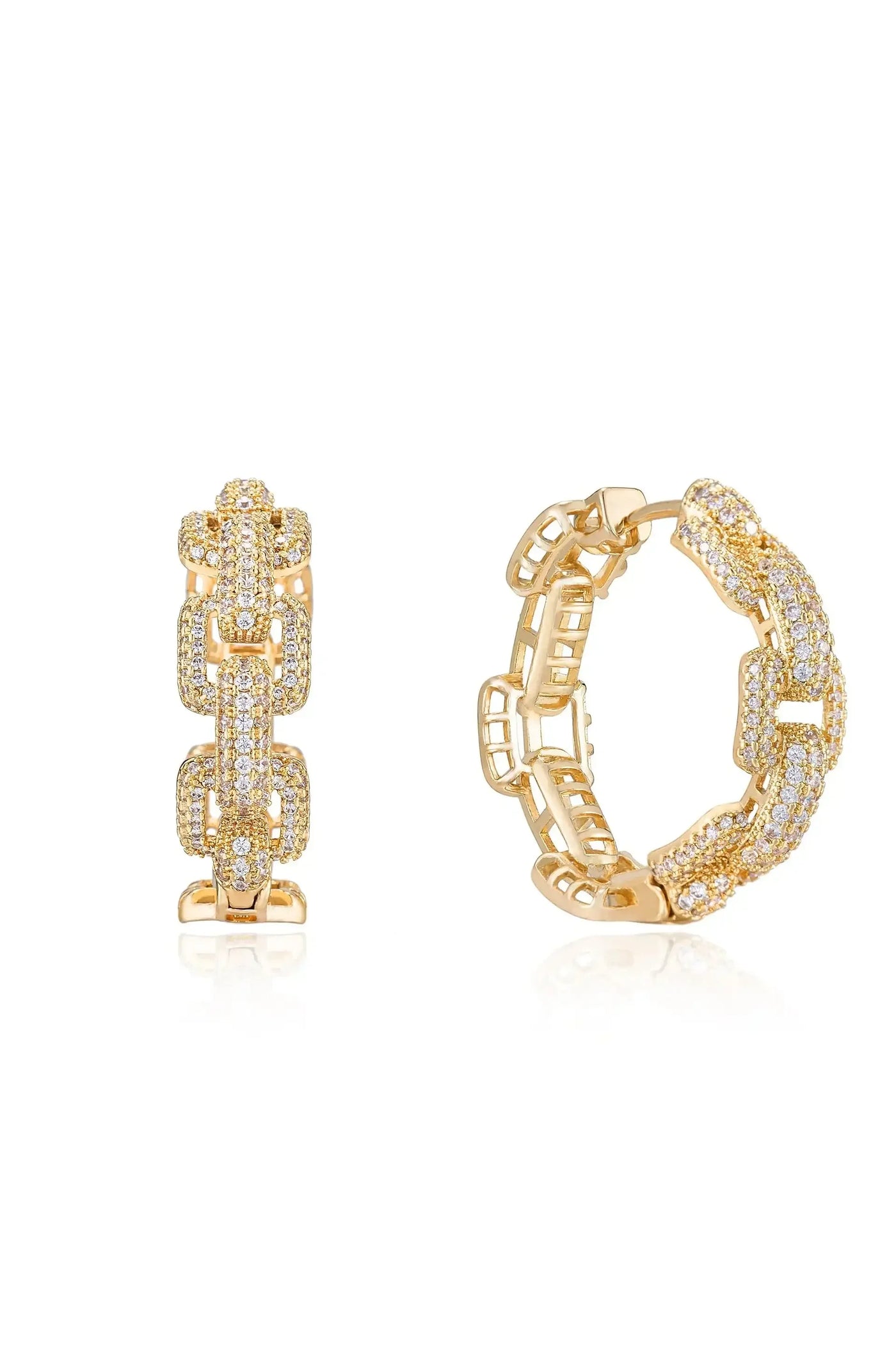 A pair of gold earrings, one with a chain-like design and the other featuring a studded pattern, rests on a reflective surface, highlighting their intricate details and shine.