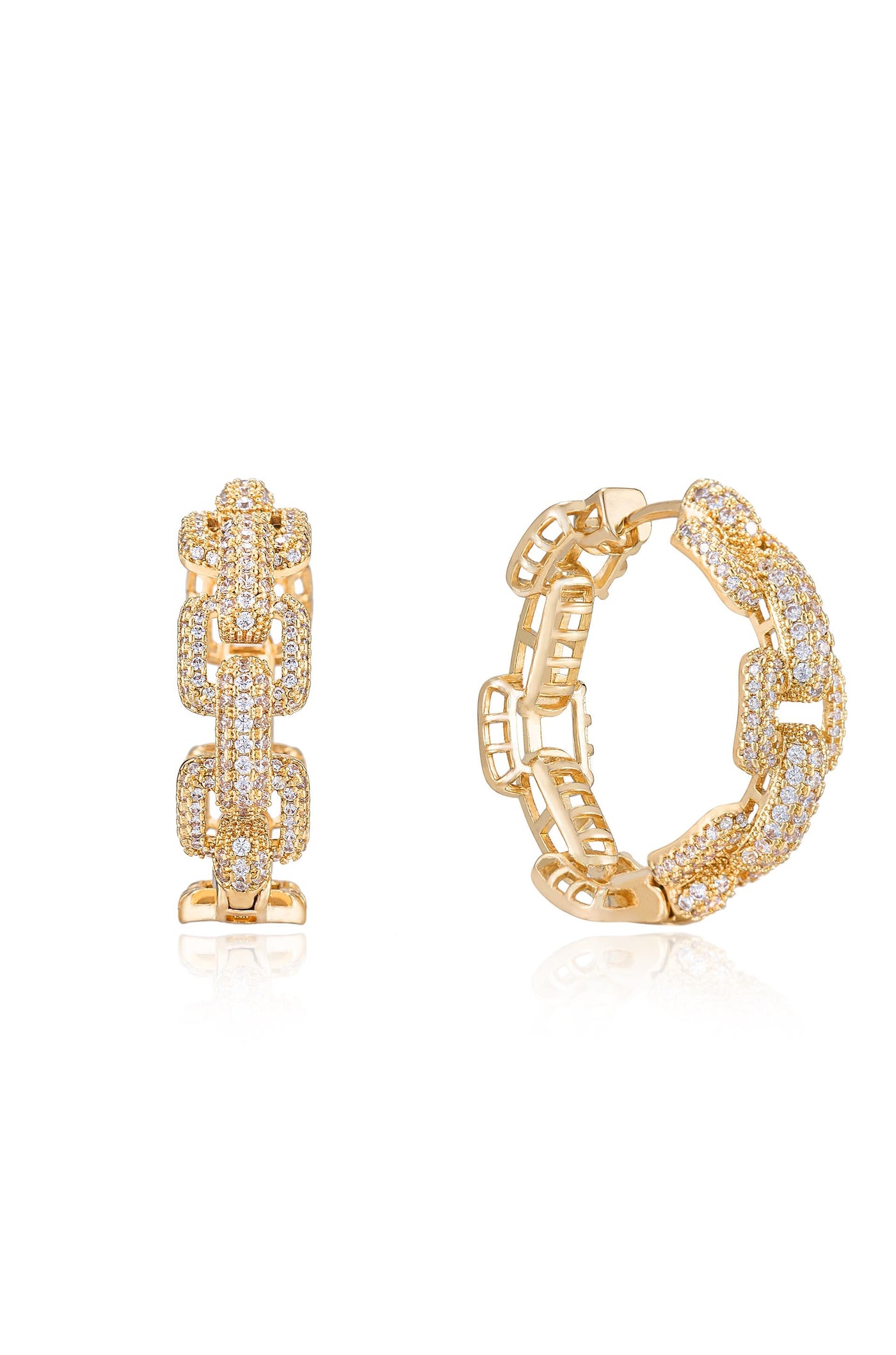 A pair of gold earrings, one with a chain-like design and the other featuring a studded pattern, rests on a reflective surface, highlighting their intricate details and shine.
