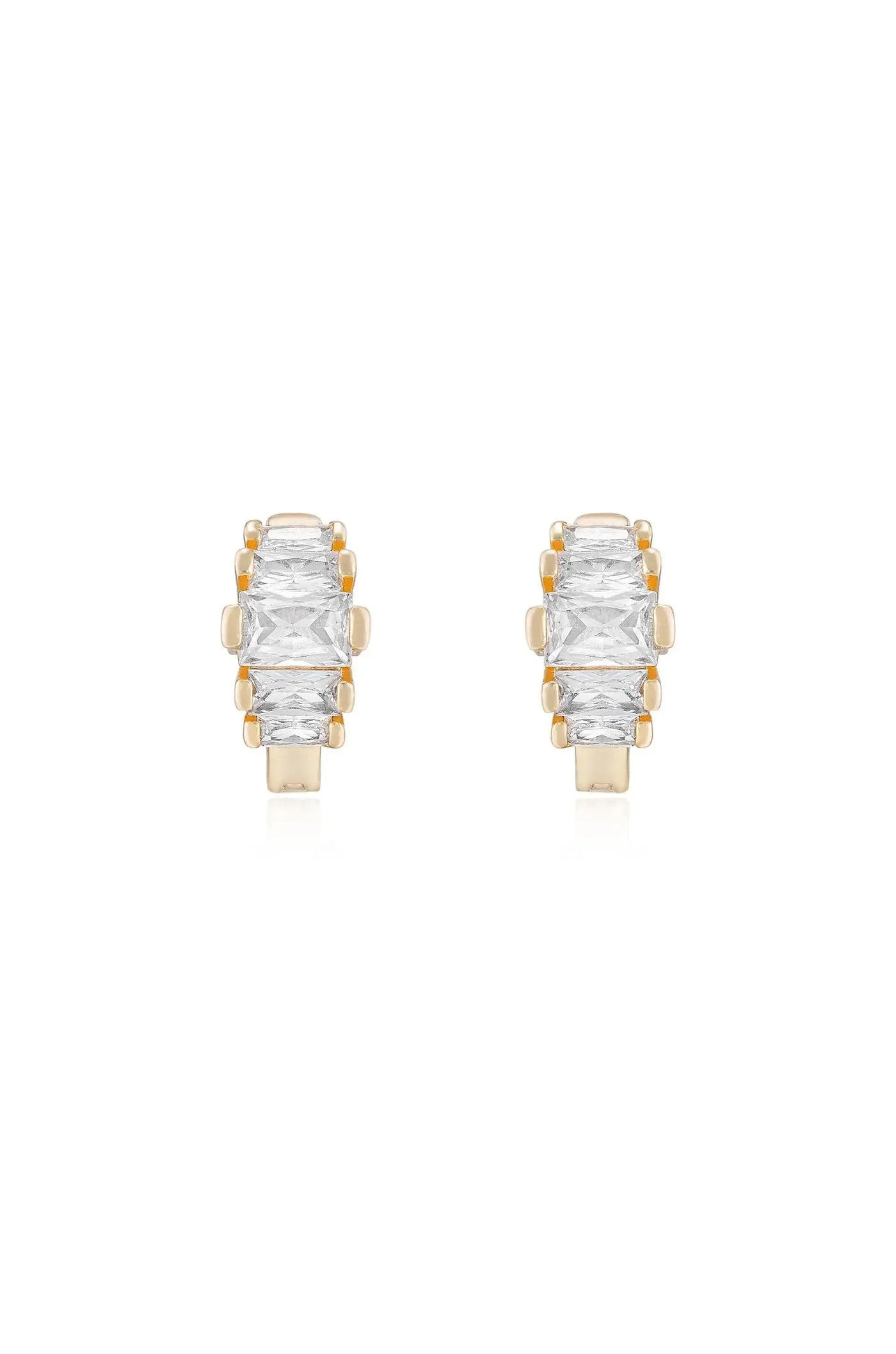Two elegant earrings featuring rectangular, clear stones set in gold settings. The earrings rest on a reflective surface, showcasing their shiny, luxurious design.