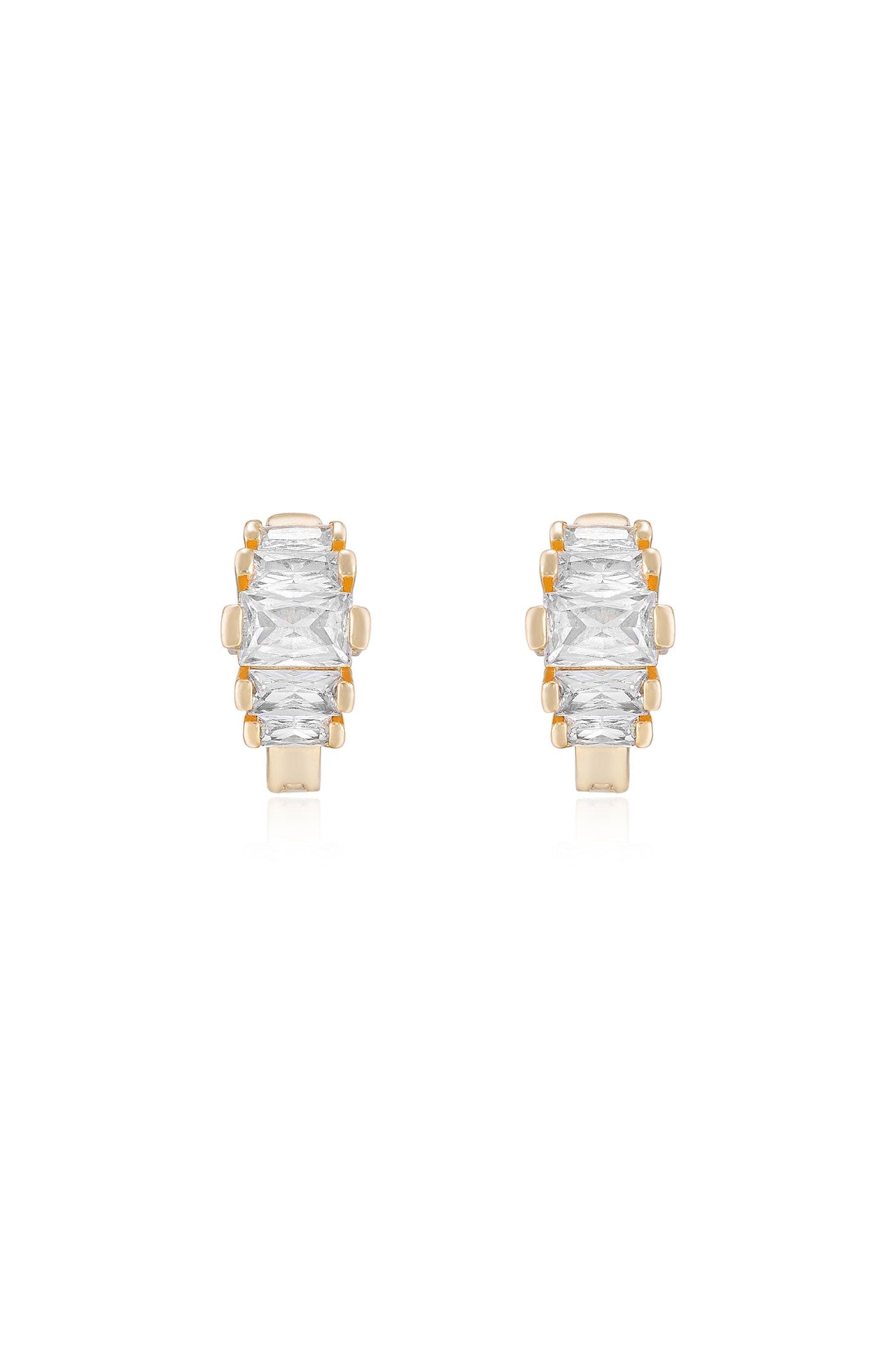 Two elegant earrings featuring rectangular, clear stones set in gold settings. The earrings rest on a reflective surface, showcasing their shiny, luxurious design.
