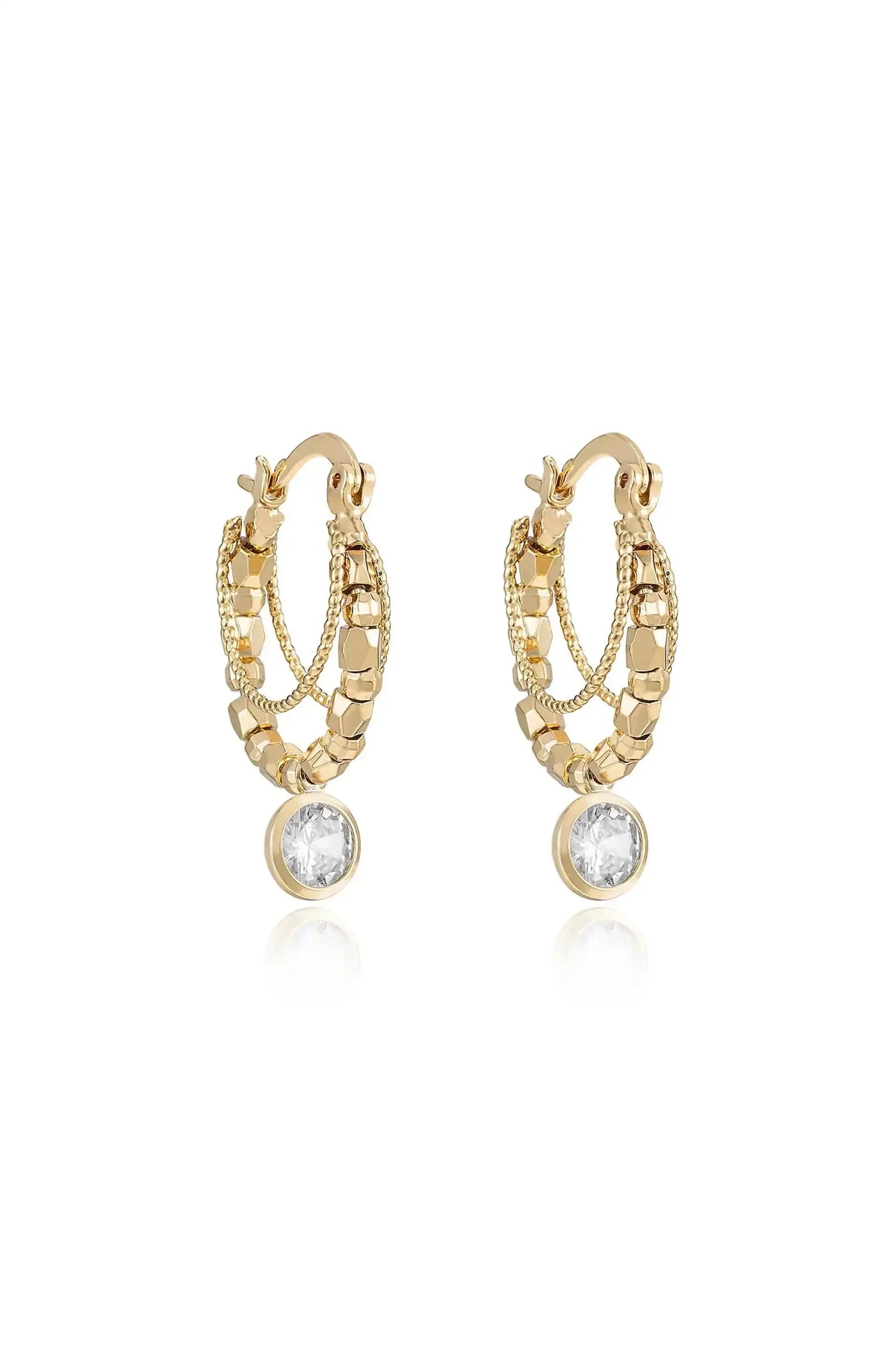 Gold hoop earrings feature intricate chain and bead detailing, with a single clear gemstone at the bottom, reflecting light, set against a neutral backdrop.
