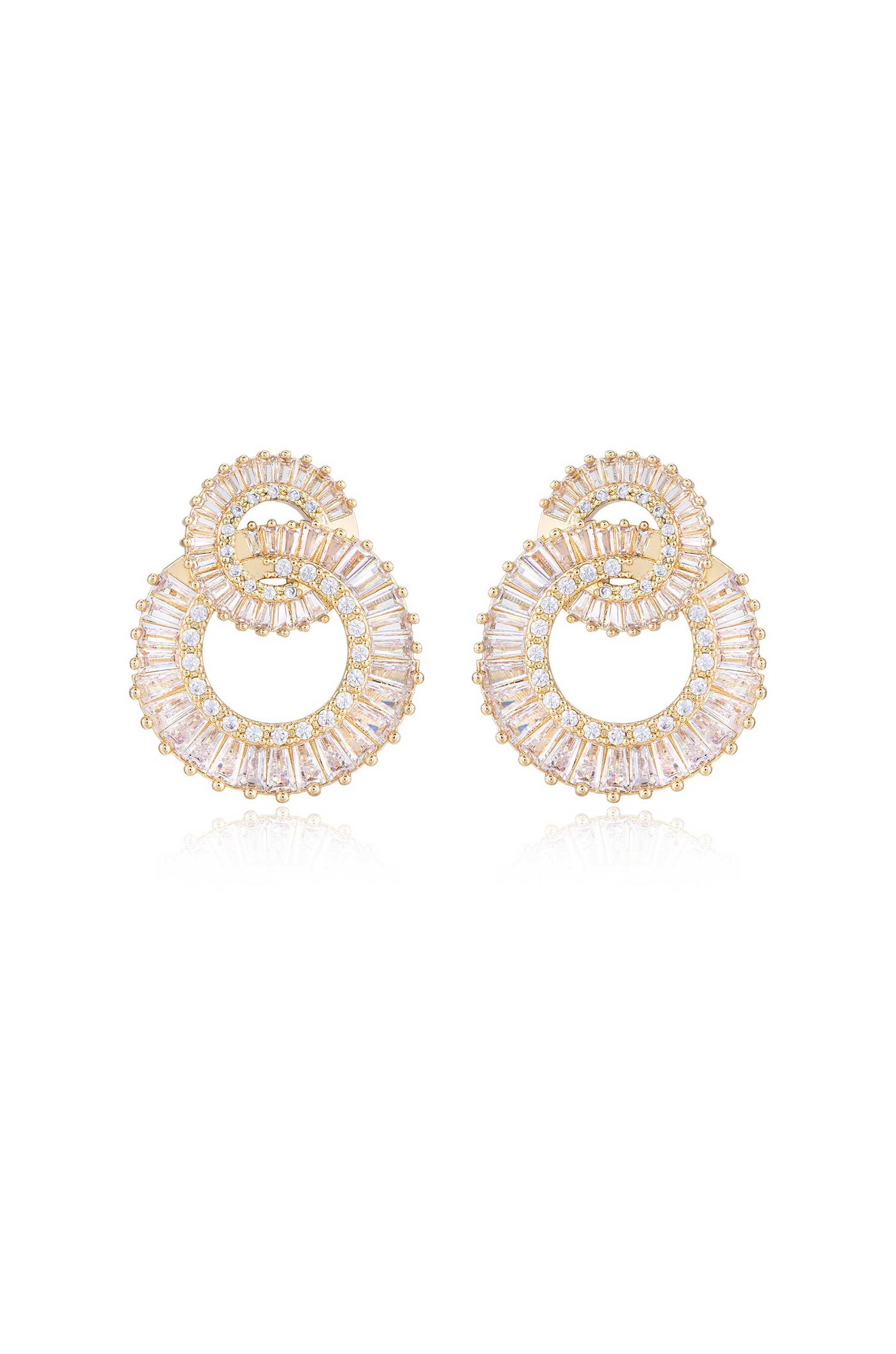 Golden hoop earrings with intricate patterns feature a spiral design filled with sparkling gemstones. They are displayed on a reflective surface, enhancing their elegance and shine.