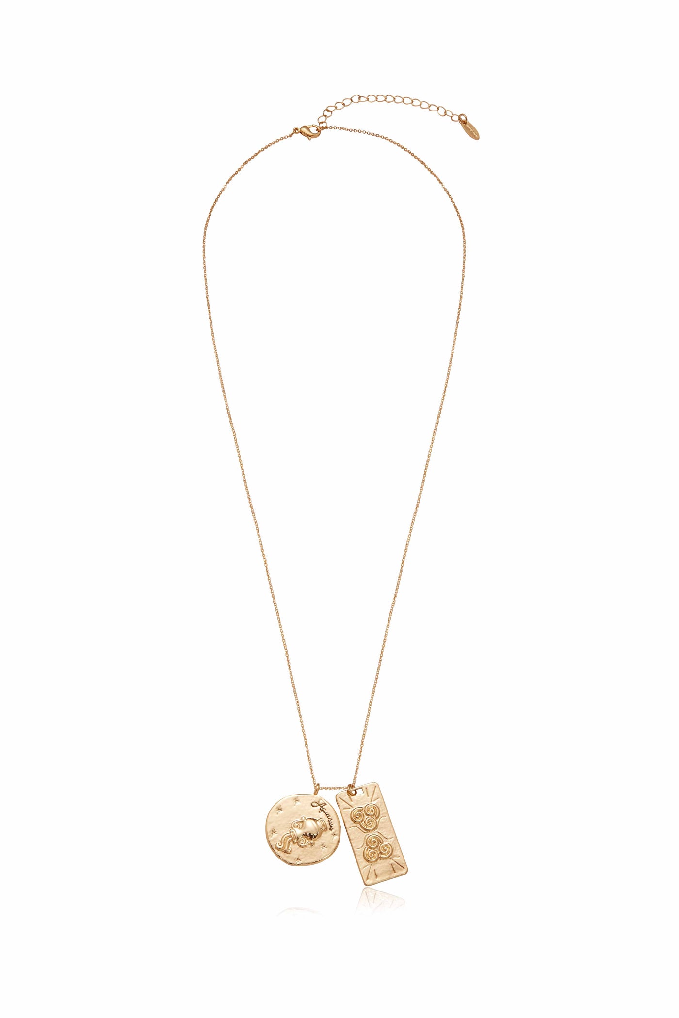 A gold necklace displays two pendants: a circular one featuring a design of a face and stars, and a rectangular one with swirls, hanging from a delicate chain.