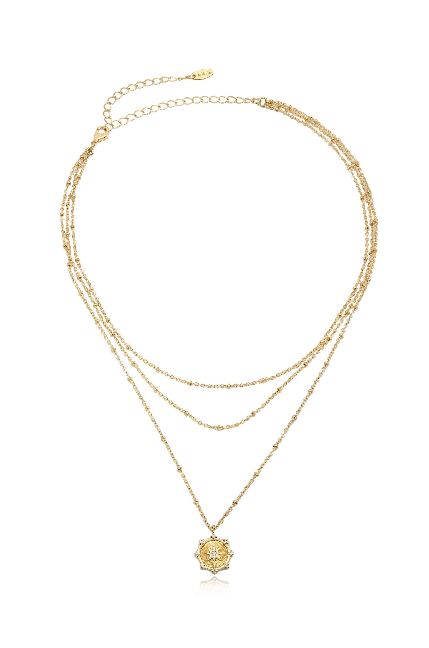A gold layered necklace features three delicate chains, adorned with small beads, and a central star-shaped pendant with intricate designs and a gemstone in the center against a white background.