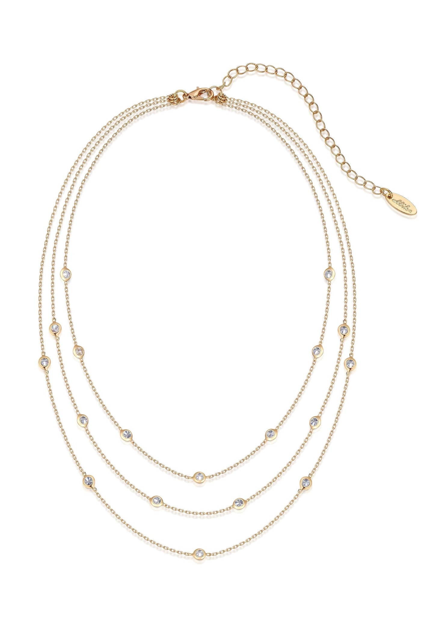 A multi-strand gold necklace features three delicate chains adorned with evenly spaced, small circular gemstones, showcasing a shimmering appearance against a light, neutral background.