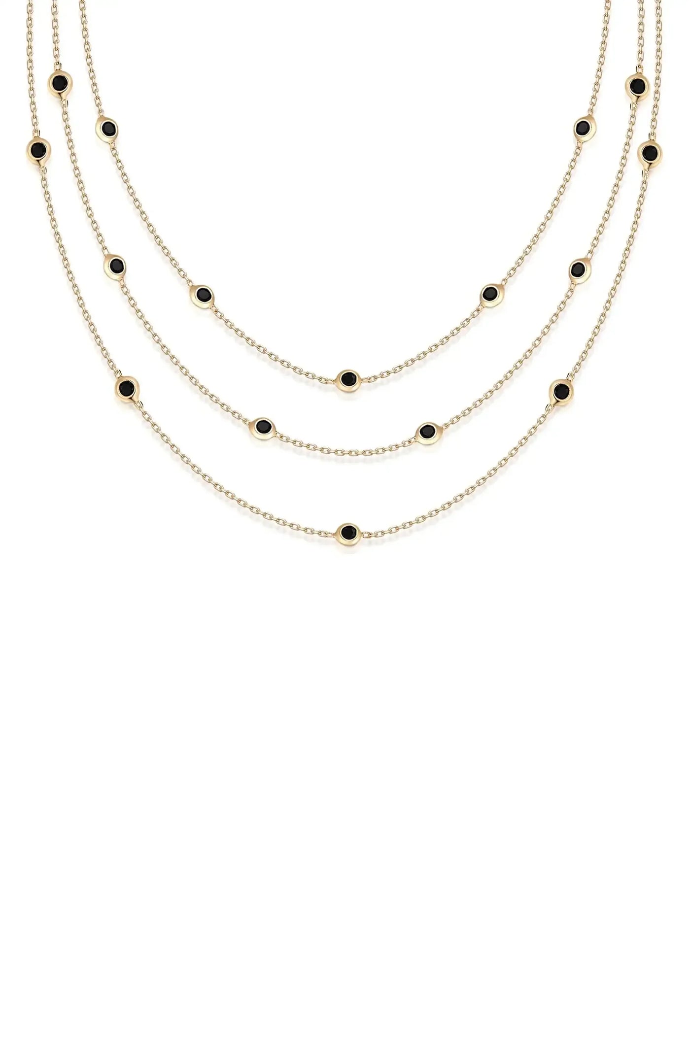 A layered gold necklace featuring multiple chains, adorned with evenly spaced circular black stones, elegantly drapes against a plain white background.