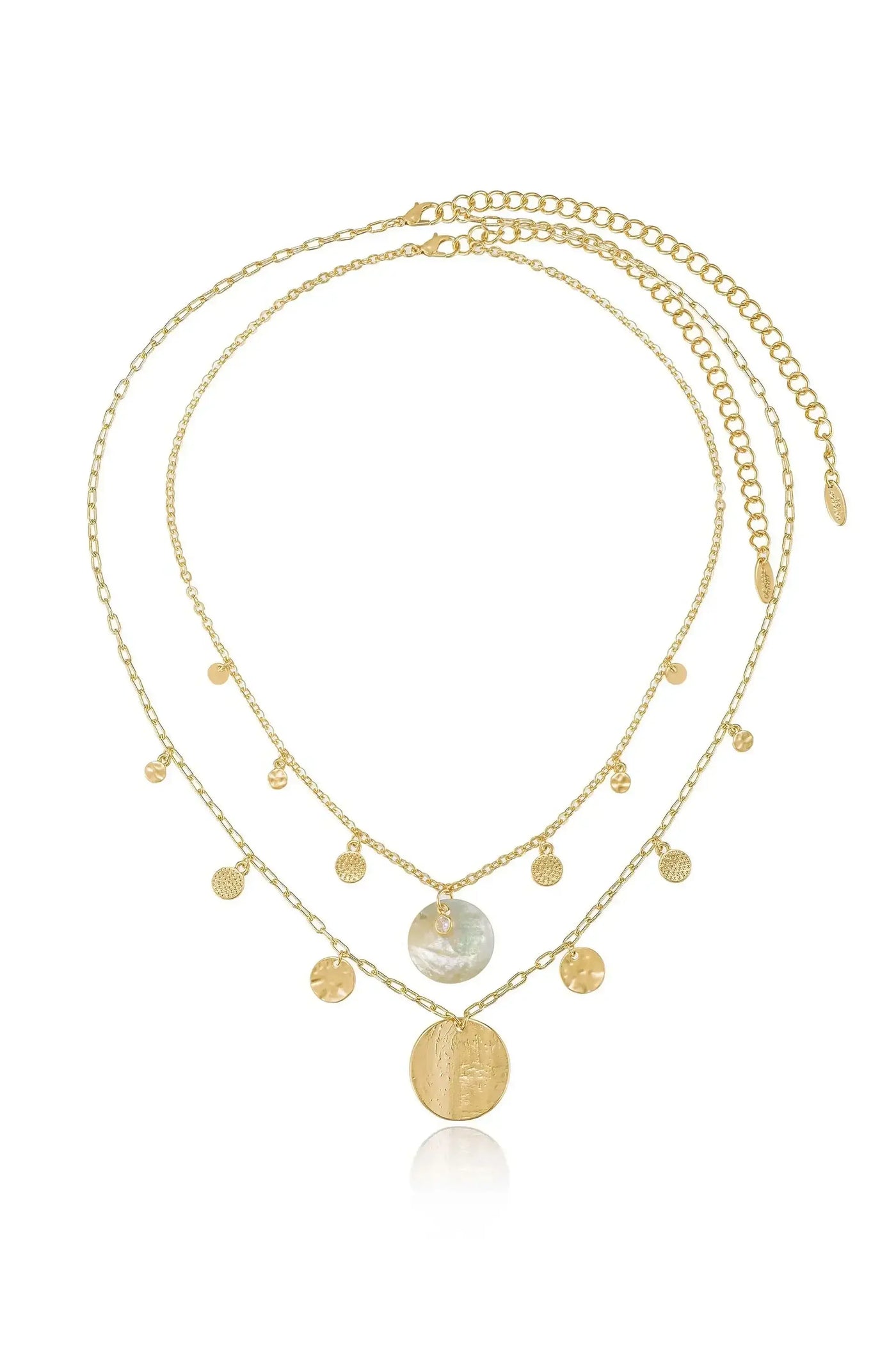 A layered gold necklace with delicate chains features a large iridescent pendant and smaller textured charms, elegantly resting on a reflective surface, showcasing its intricate design.
