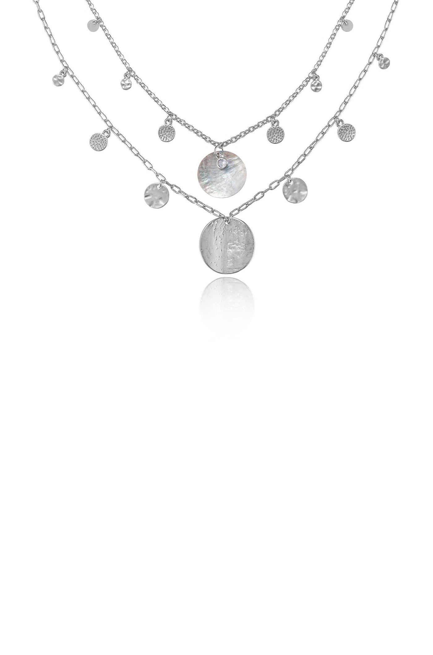 A layered silver necklace features multiple chains with decorative circular pendants and small gems, suspended in a reflective space, emphasizing its elegant design and shine.