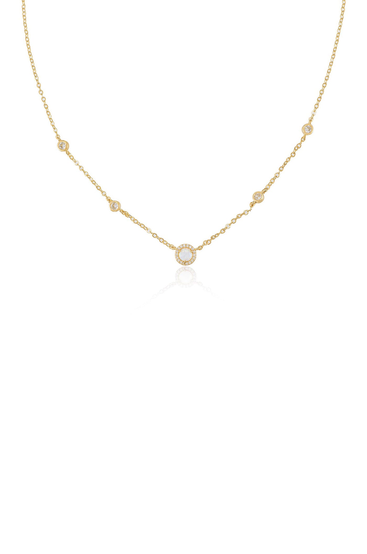 A delicate gold necklace features a circular pendant surrounded by smaller stones, elegantly draping with a reflective sheen against a plain white background.