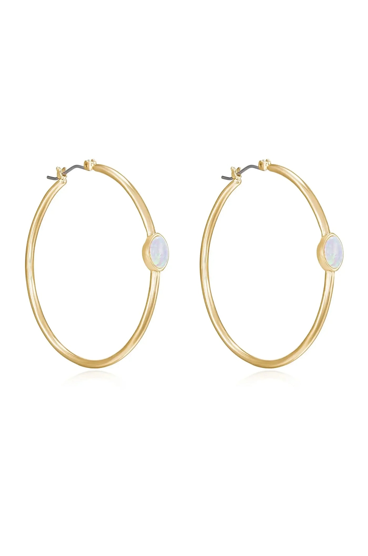 Gold hoop earrings are displayed prominently, showcasing a smooth, large circular shape with a small opal stone set at one side, against a plain background emphasizing their elegance.