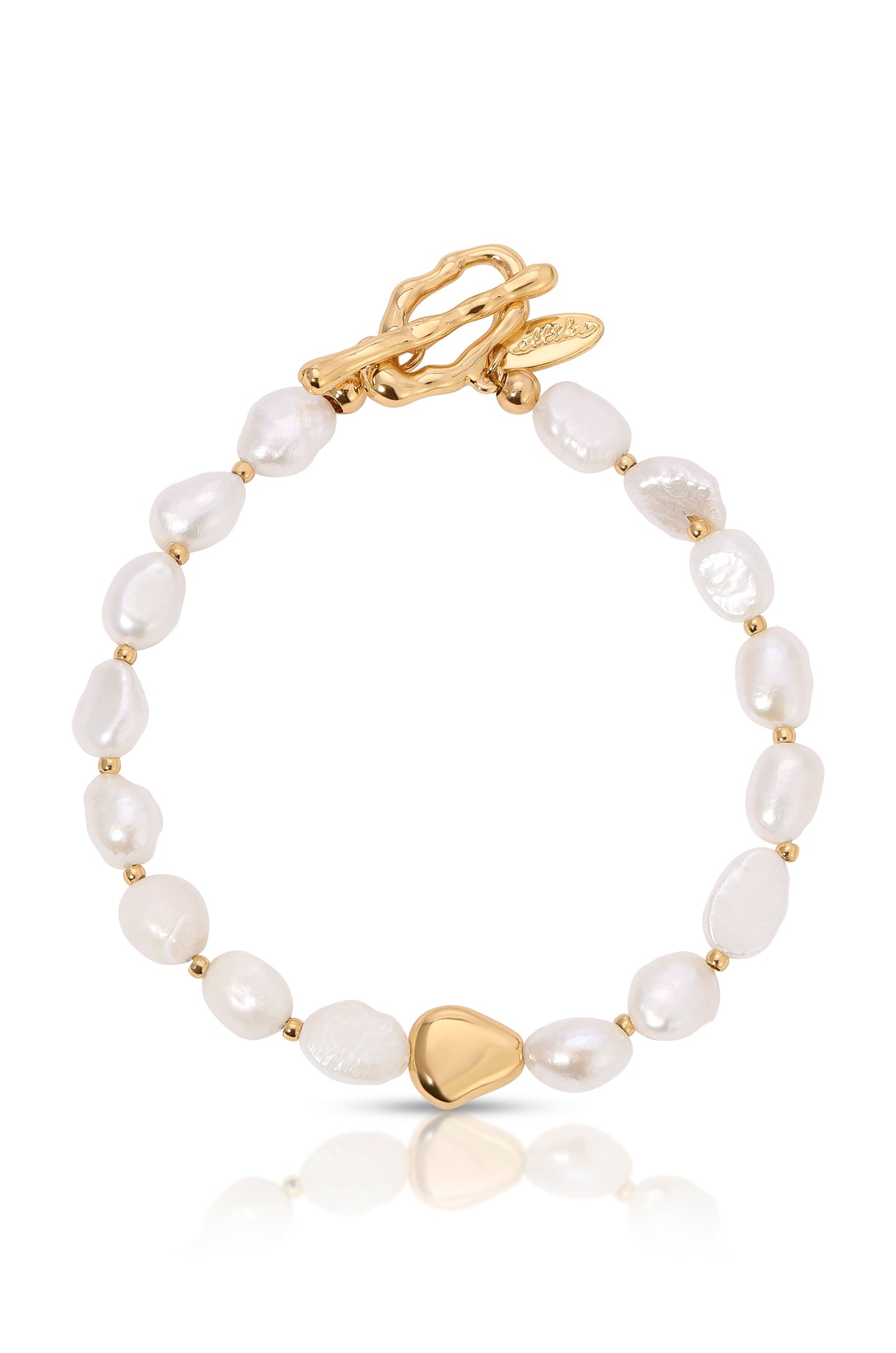 A pearl bracelet features irregularly shaped white pearls interspersed with small gold beads, culminating in a triangular gold clasp. The piece rests on a reflective surface, showcasing its elegance.