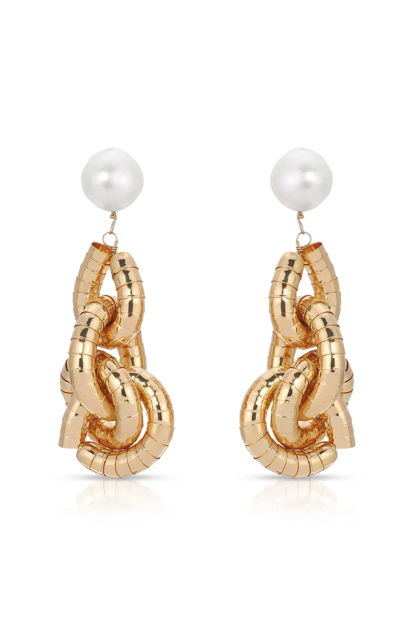 Two gold-colored earrings shaped like intertwined links feature a shiny white spherical bead at the top. They are displayed against a reflective background.