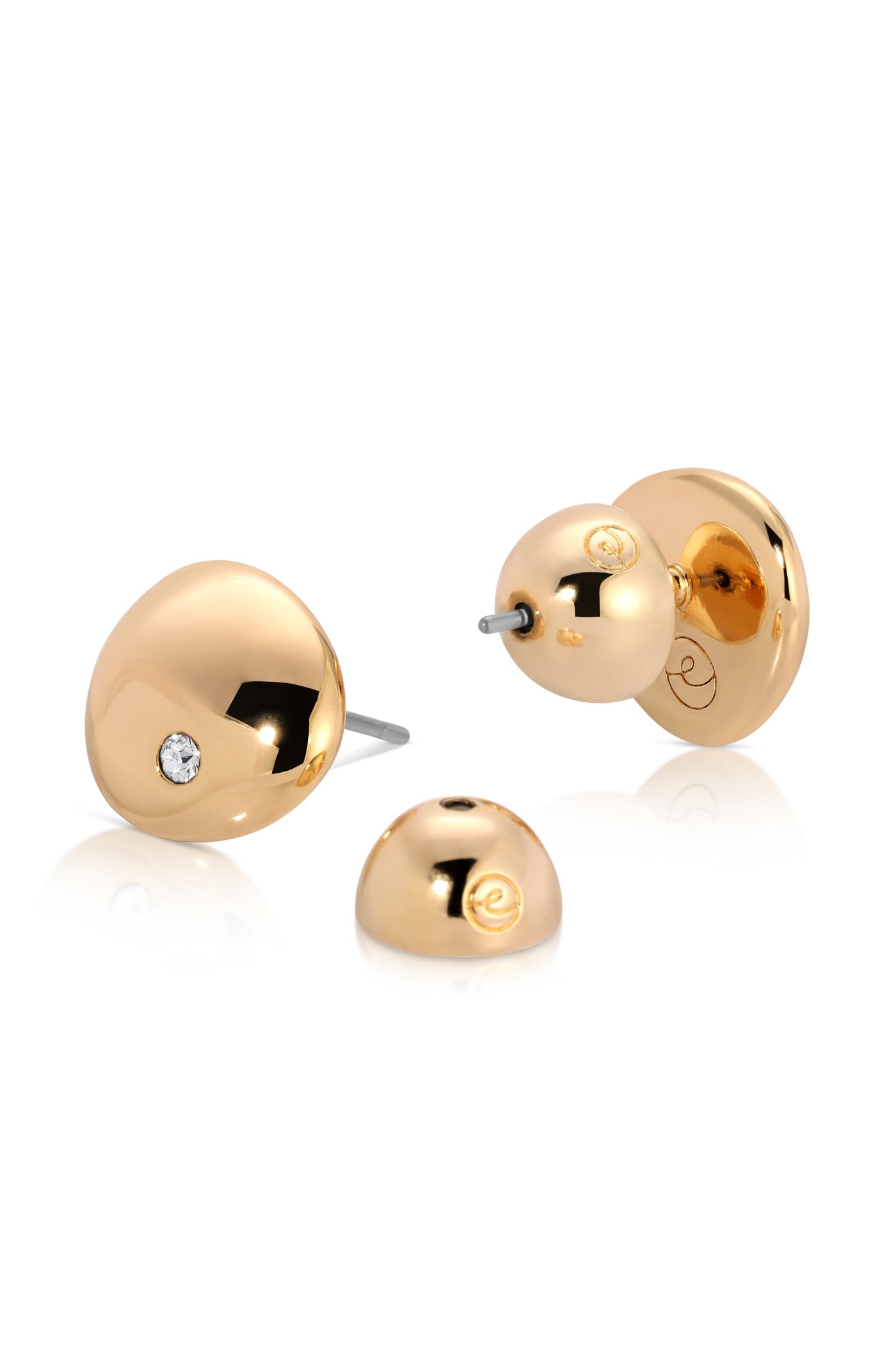 Two golden stud earrings are displayed, one with a sparkling stone, showcasing their shiny surface. They rest against a plain white background, emphasizing their elegant design and luxurious appearance.
