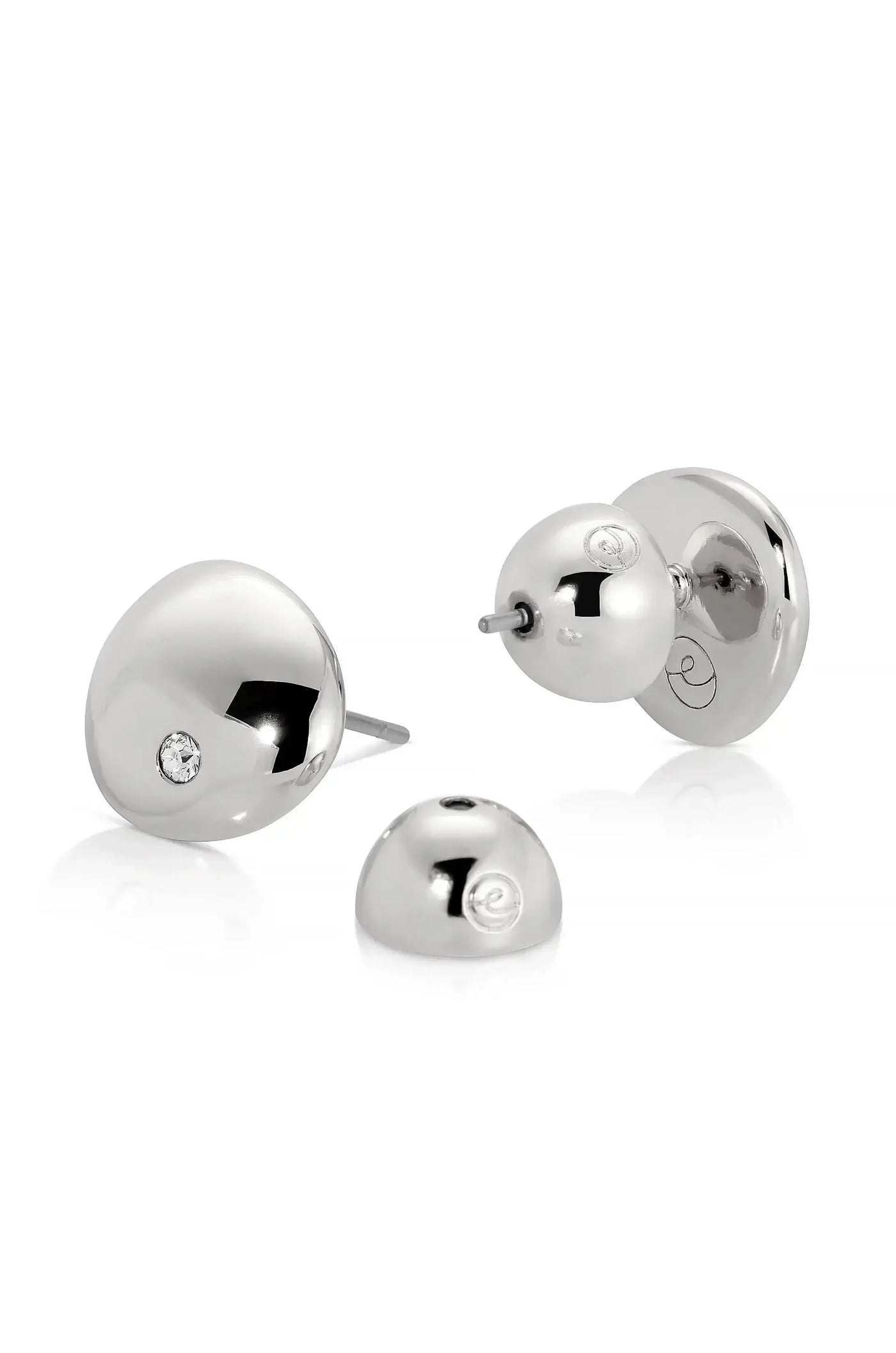 Silver earrings with a polished, rounded design are displayed. One earring features a small diamond, while another earring backing sits beside them on a white background, emphasizing their elegant appearance.