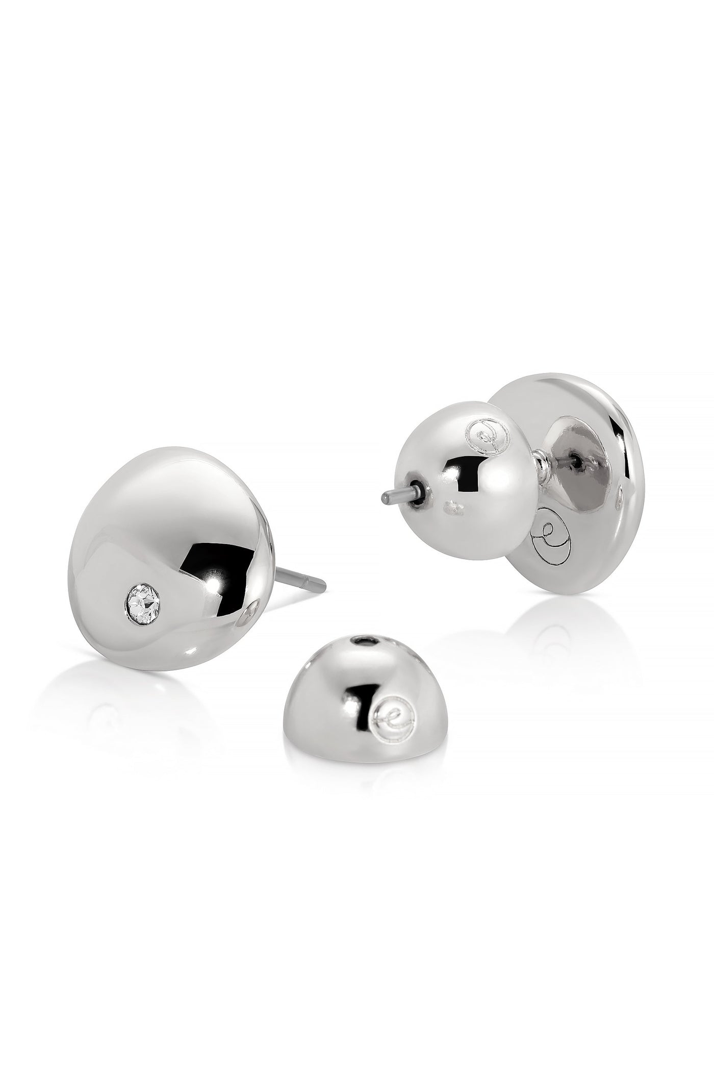 Silver earrings with a polished, rounded design are displayed. One earring features a small diamond, while another earring backing sits beside them on a white background, emphasizing their elegant appearance.