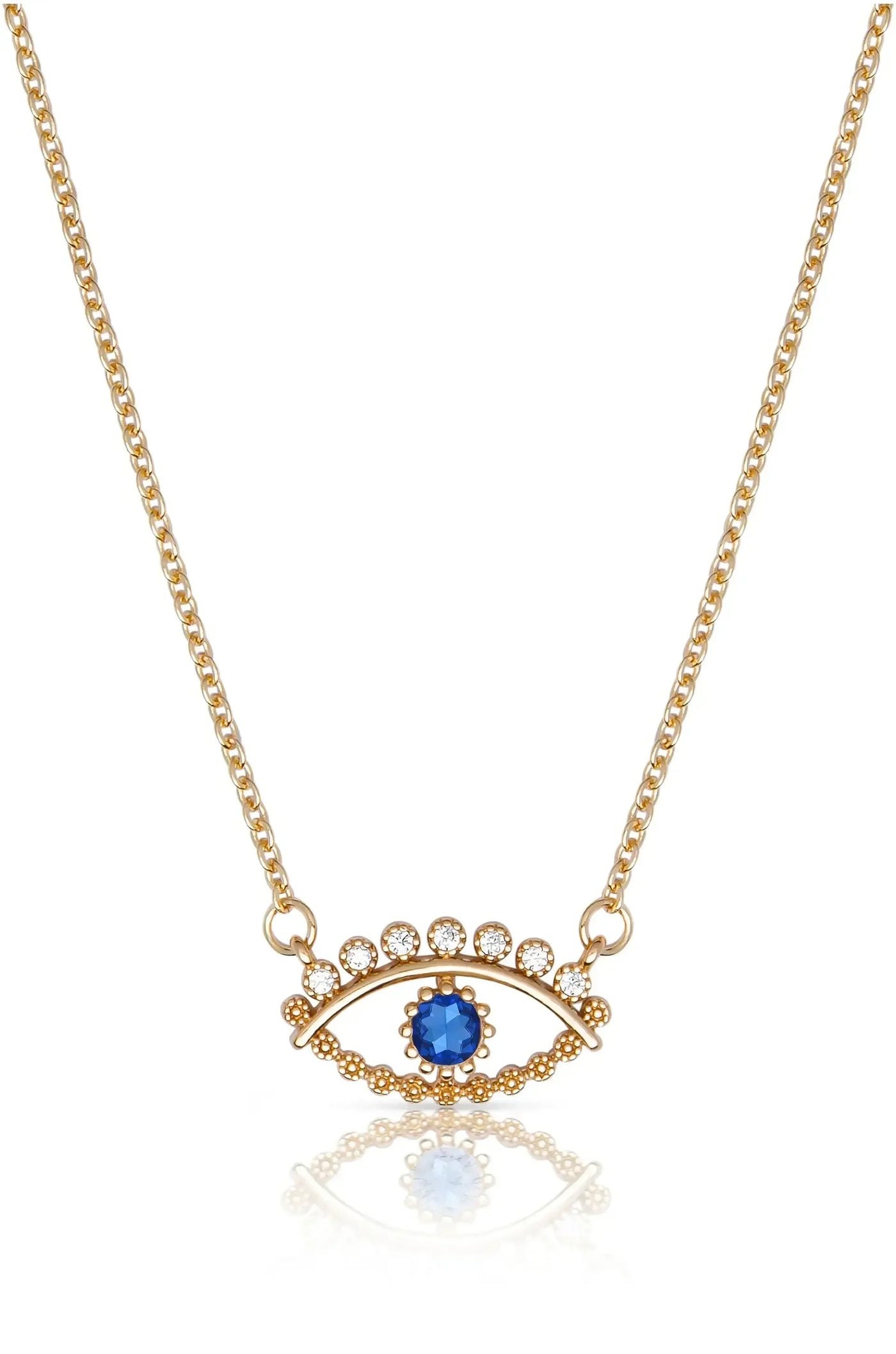 A golden necklace features a blue gemstone and sparkling circular decorations arranged in an eye shape, resting on a reflective surface, showcasing its intricate design and elegance.