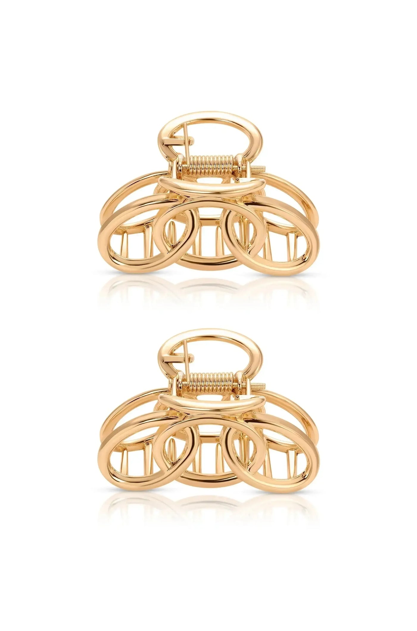 A golden hair clip featuring intertwined circular shapes sits centered, showcasing its reflective surface against a plain white background, emphasizing its design and texture.