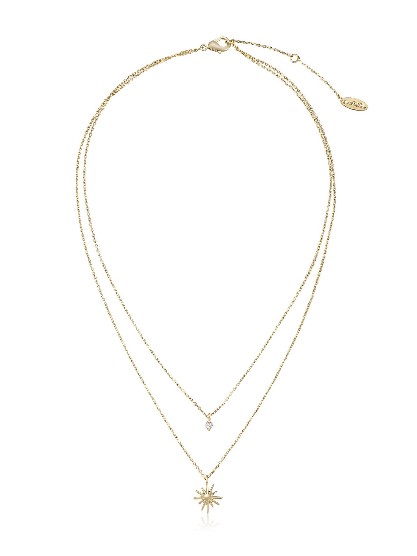 A gold necklace with two chains: one short with a diamond-shaped pendant, and a longer chain featuring a starburst pendant, displayed against a plain white background.