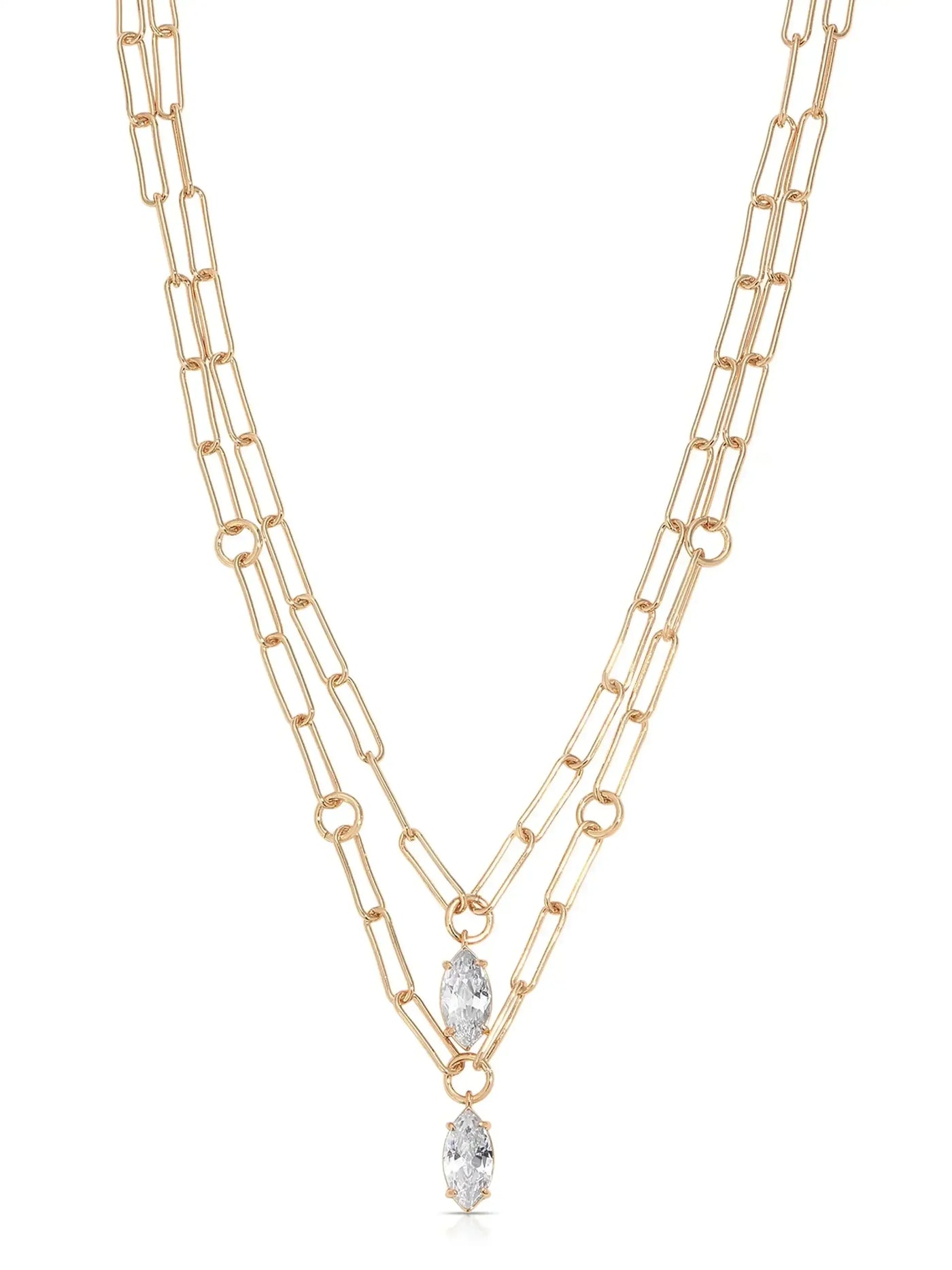 A gold chain necklace features two layered strands with elongated links. At the center, two marquise-cut crystals dangle, enhancing the jewelry's elegance against a neutral background.