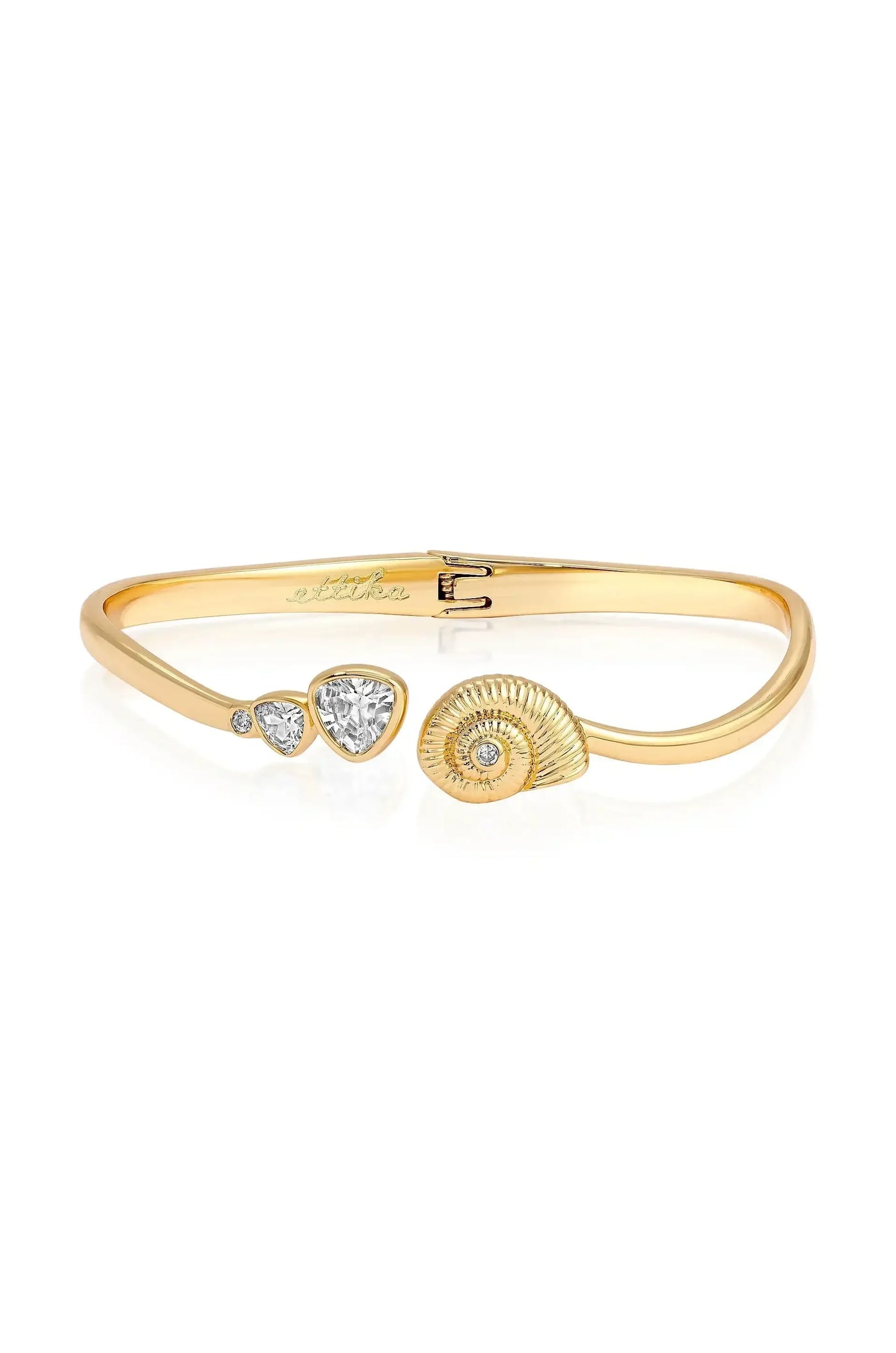 A gold bracelet features a shell design and several diamonds, including two pear-shaped stones and a round diamond, reflecting elegance against a white background.