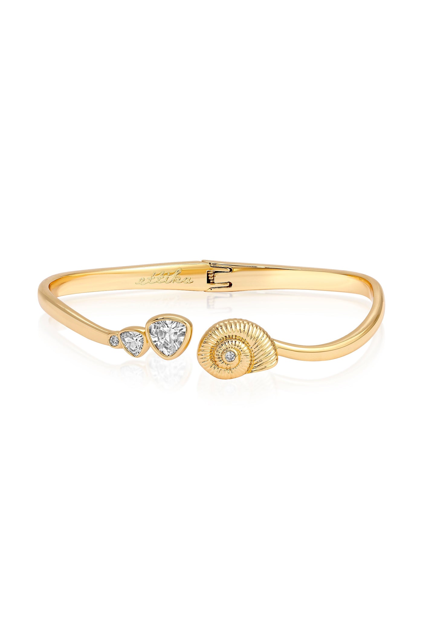 A gold bracelet features a shell design and several diamonds, including two pear-shaped stones and a round diamond, reflecting elegance against a white background.