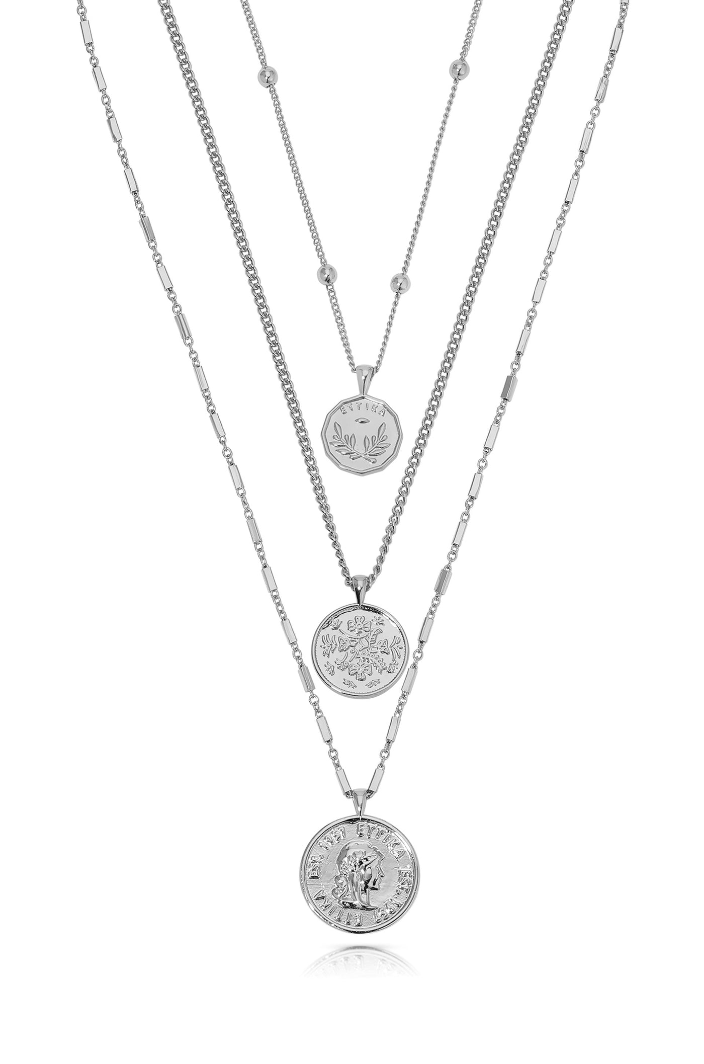 Three silver necklaces hang vertically. The top has a small pendant, while the middle features a round medallion design, and the bottom showcases a larger, detailed circular pendant.