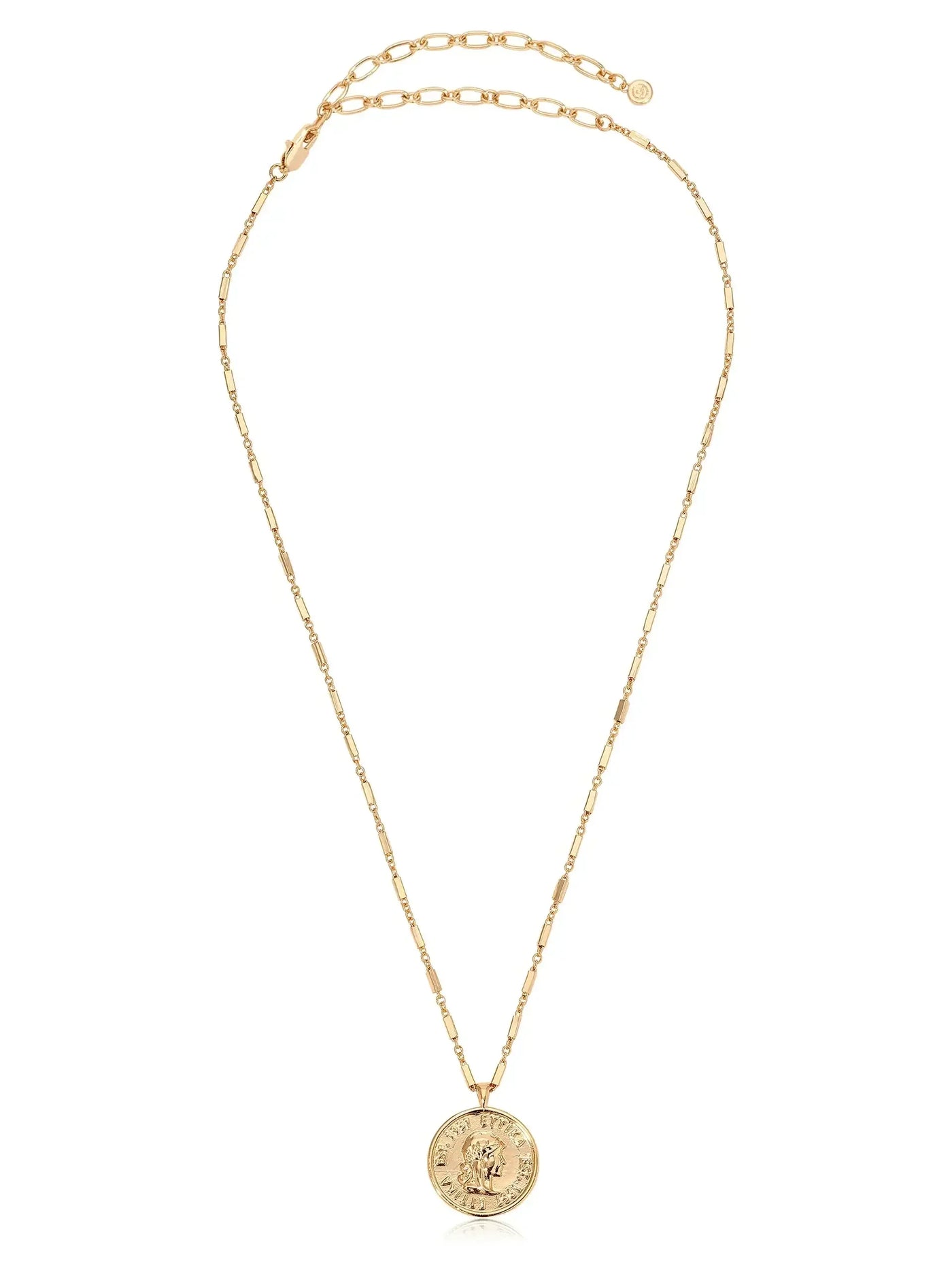 A gold necklace features a delicate chain with an ornate circular pendant displaying a detailed design. The necklace appears elegant and is set against a neutral background.