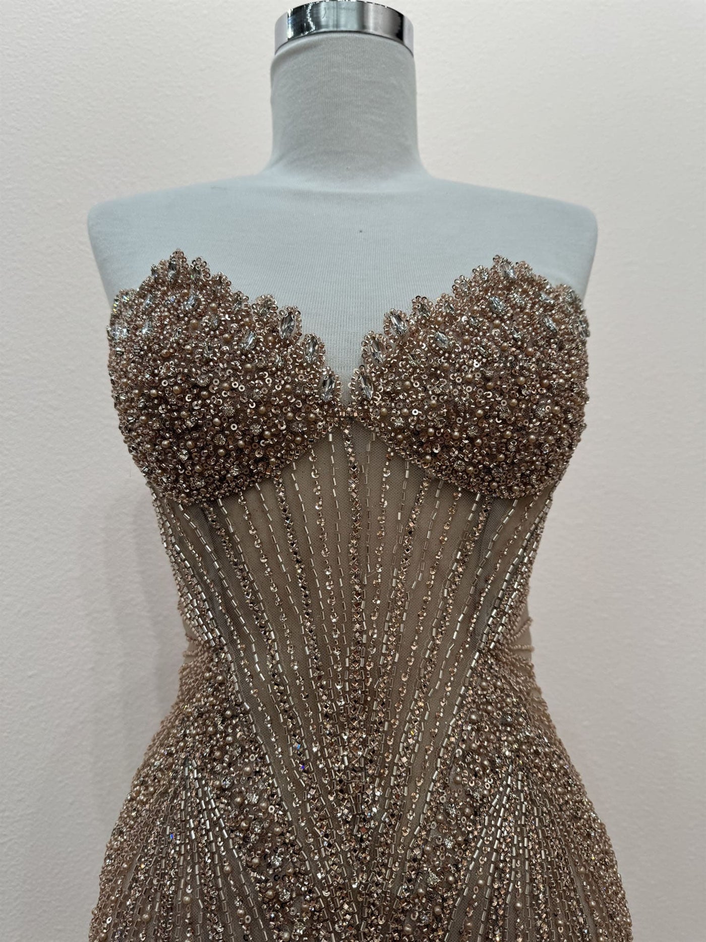 Beaded evening gown on a mannequin against a plain background