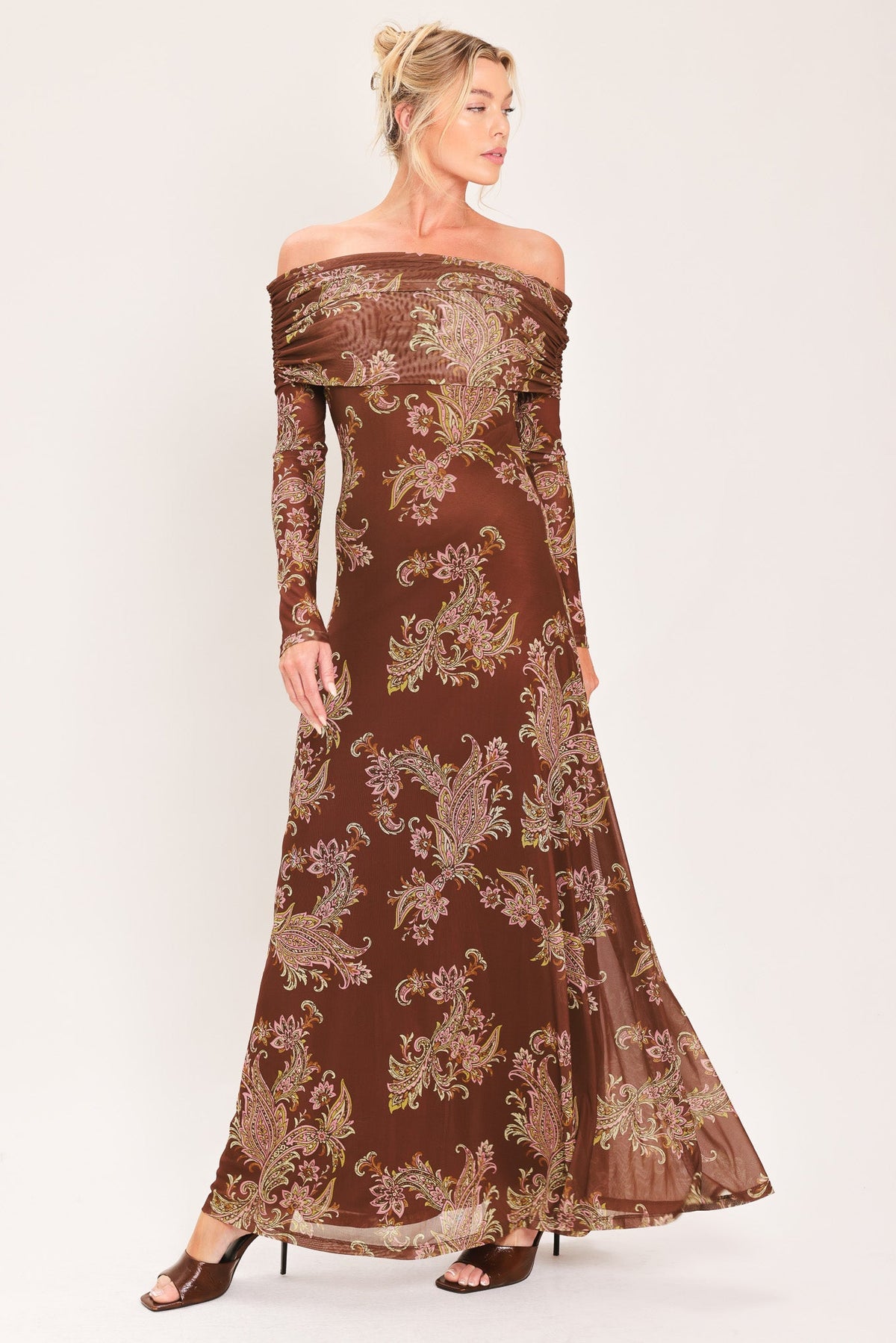 BURNT SIENNA SERENADE POWER MESH MAXI MAXI DRESS | Lady Black Tie | A woman modeling an off-the-shoulder long-sleeve maxi dress in brown with a beige paisley pattern, set against a plain light background.