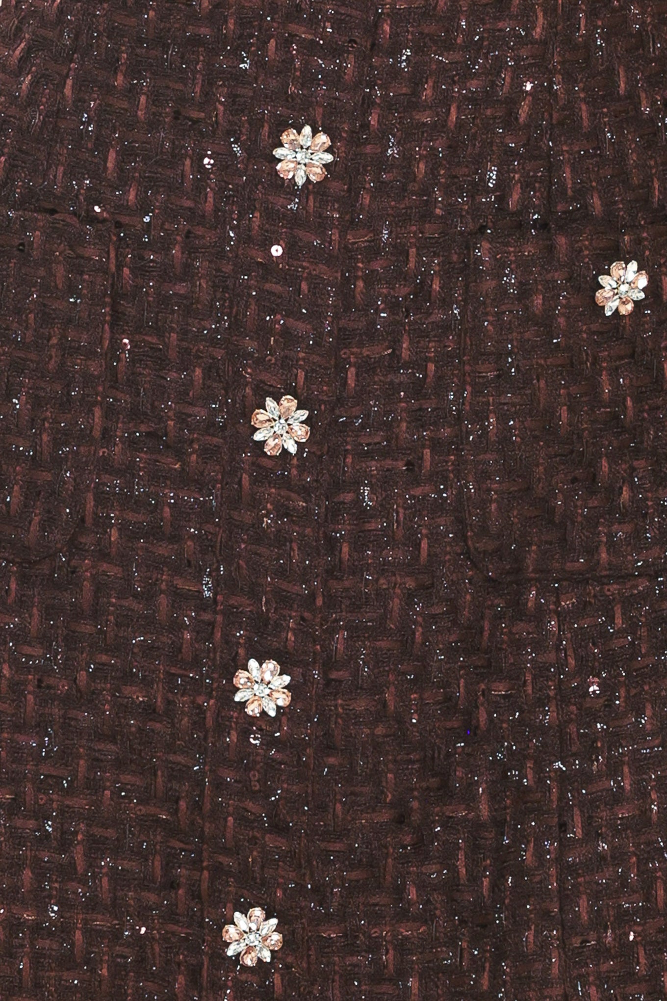 Chocolate Muse Tweed Mini Dress | Lady Black Tie | A close-up of a dark brown textured fabric with a subtle woven pattern and scattered small silver sequins, decorated with five metallic floral embellishments.