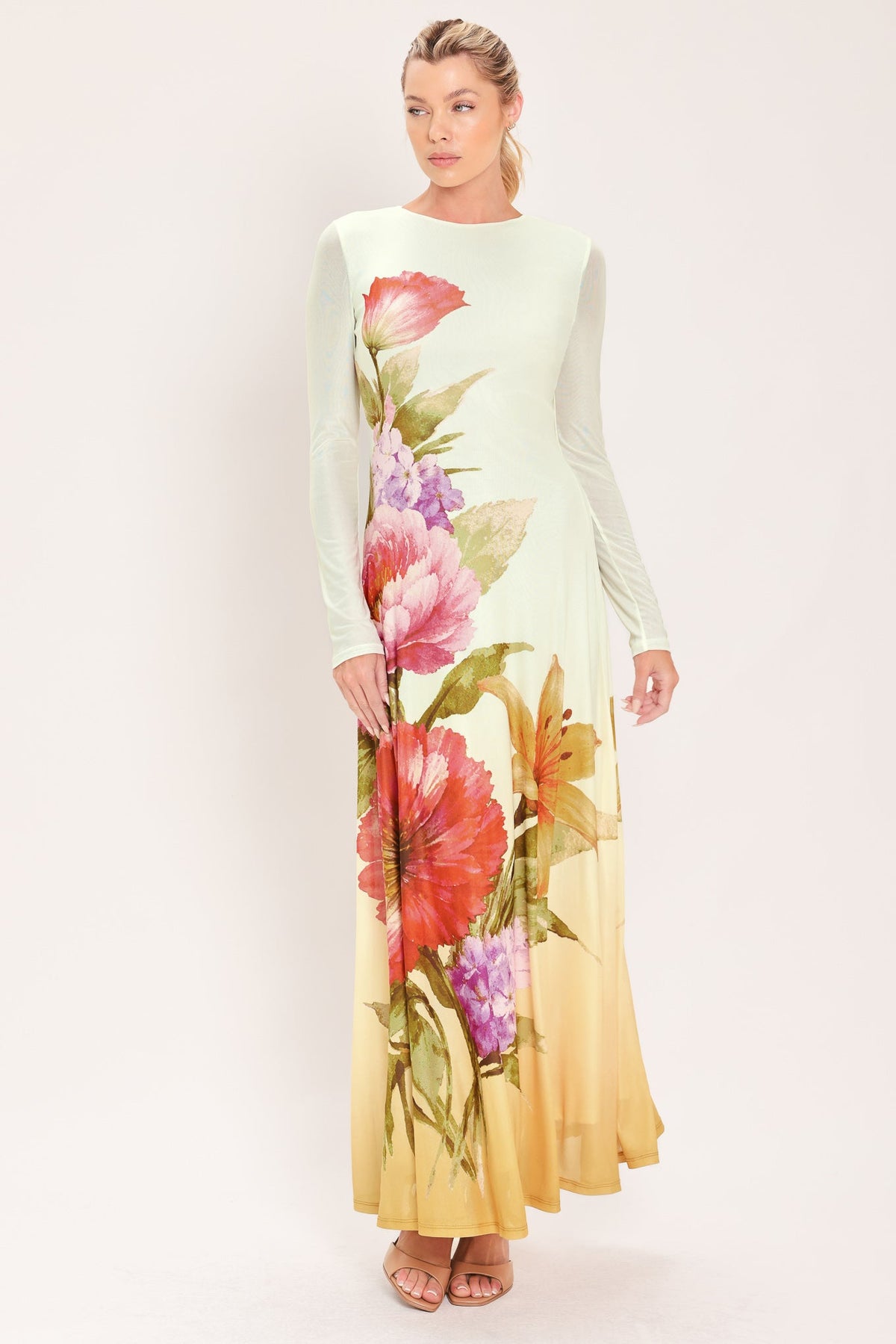 PASTEL BOTANIC SPLENDOR POWER MESH MAXI DRESS | Lady Black Tie | A woman modeling a long-sleeve maxi dress with a pale mint green top that fades into a warm yellow-orange at the hem, decorated with a large floral print in pink, red, purple, and green.