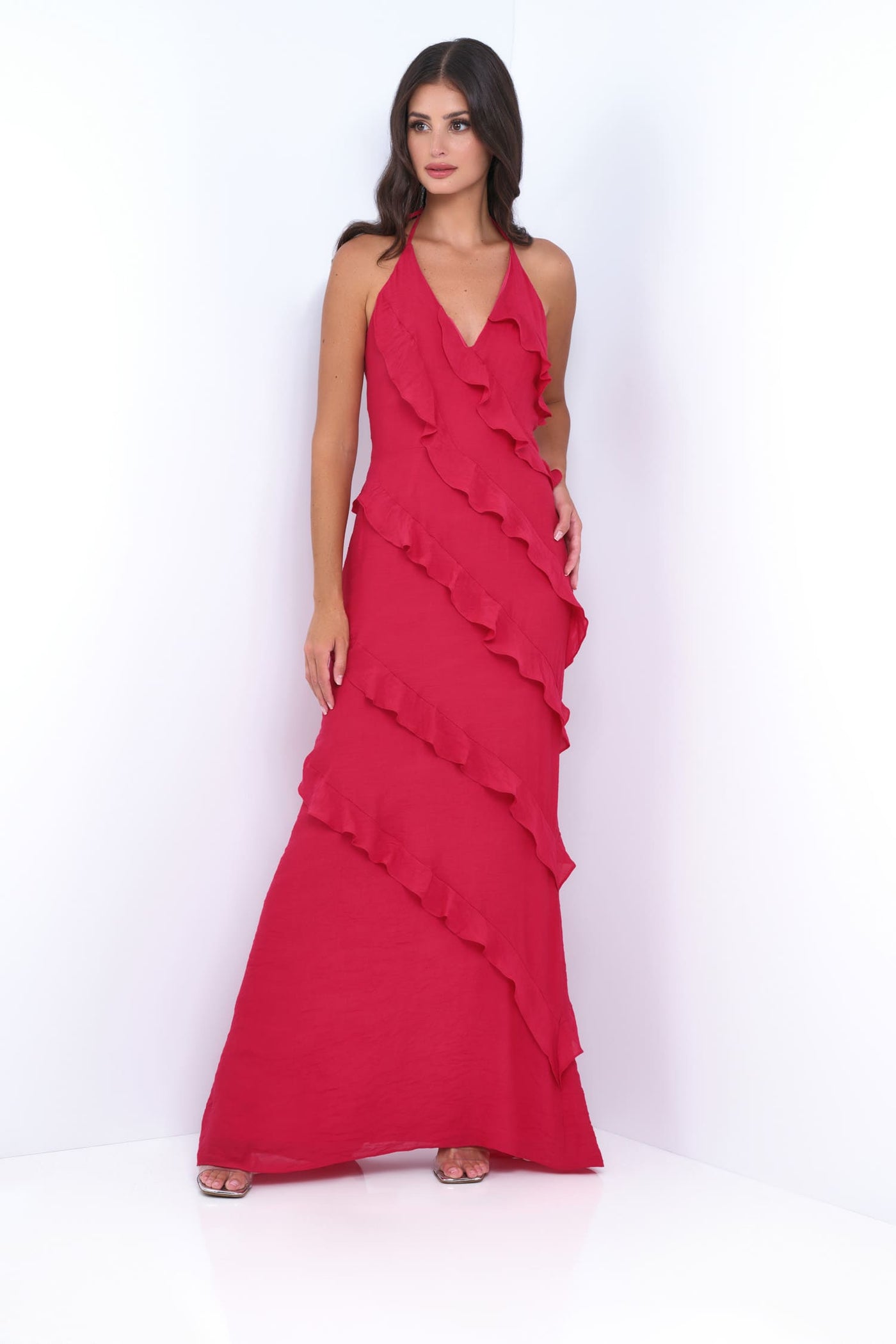 Woman wearing a red evening gown with ruffled layers on a white background