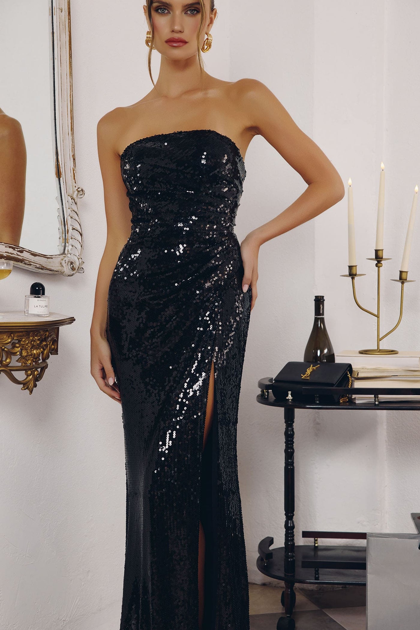 Woman wearing a black sequin strapless gown in an elegant room setting.