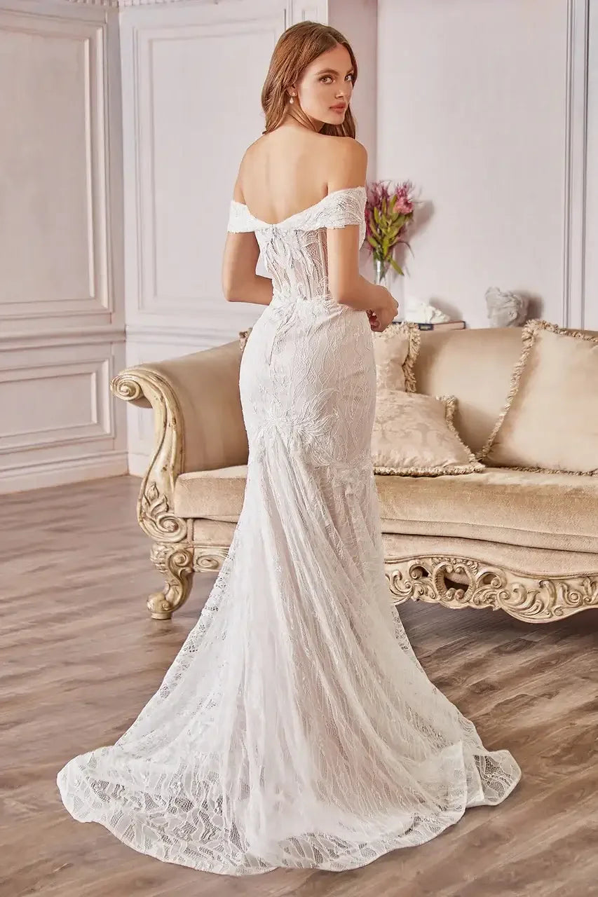 A woman wears an elegant lace wedding gown, standing gracefully in a stylish room with a vintage couch and soft lighting, exuding elegance and charm.