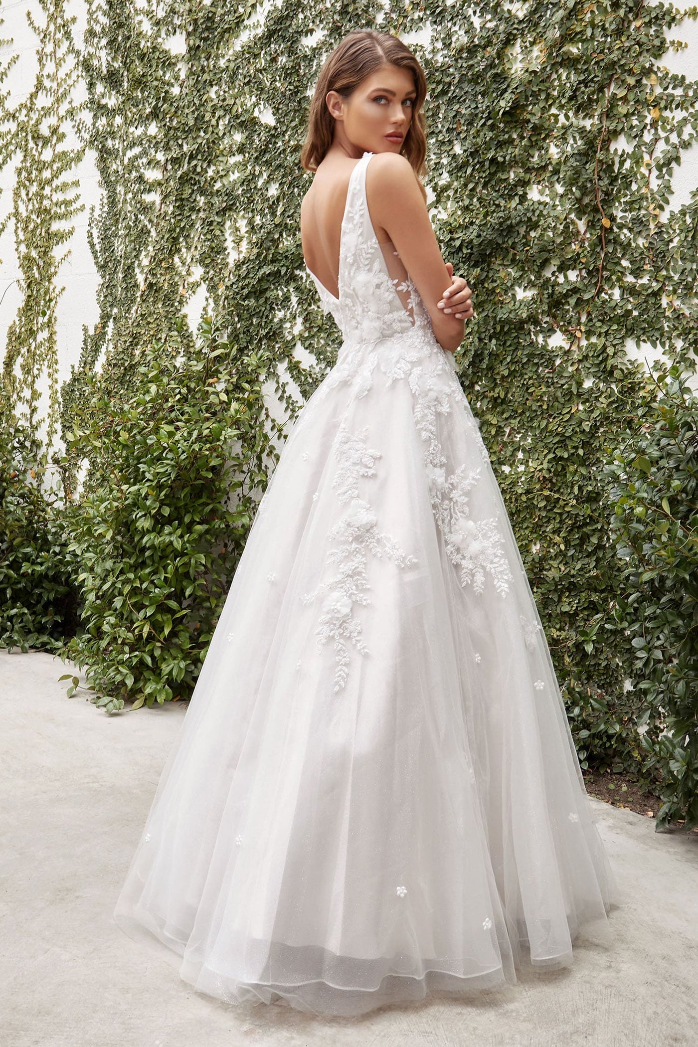 Woman in a white wedding dress standing in front of greenery
