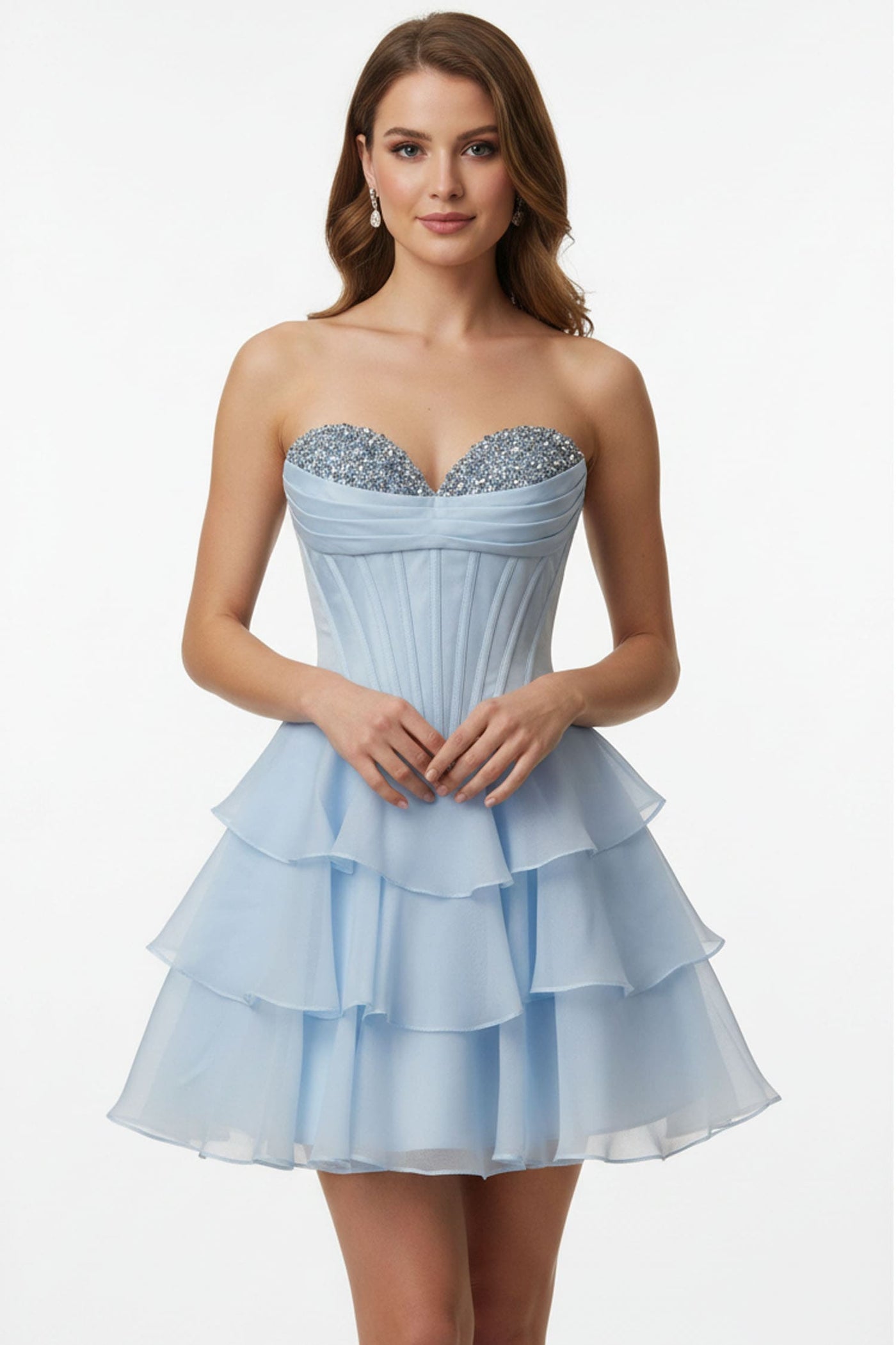 A woman modeling a strapless light blue mini dress with a sweetheart neckline, silver beaded bodice, and a tiered ruffled skirt against a plain white studio background.