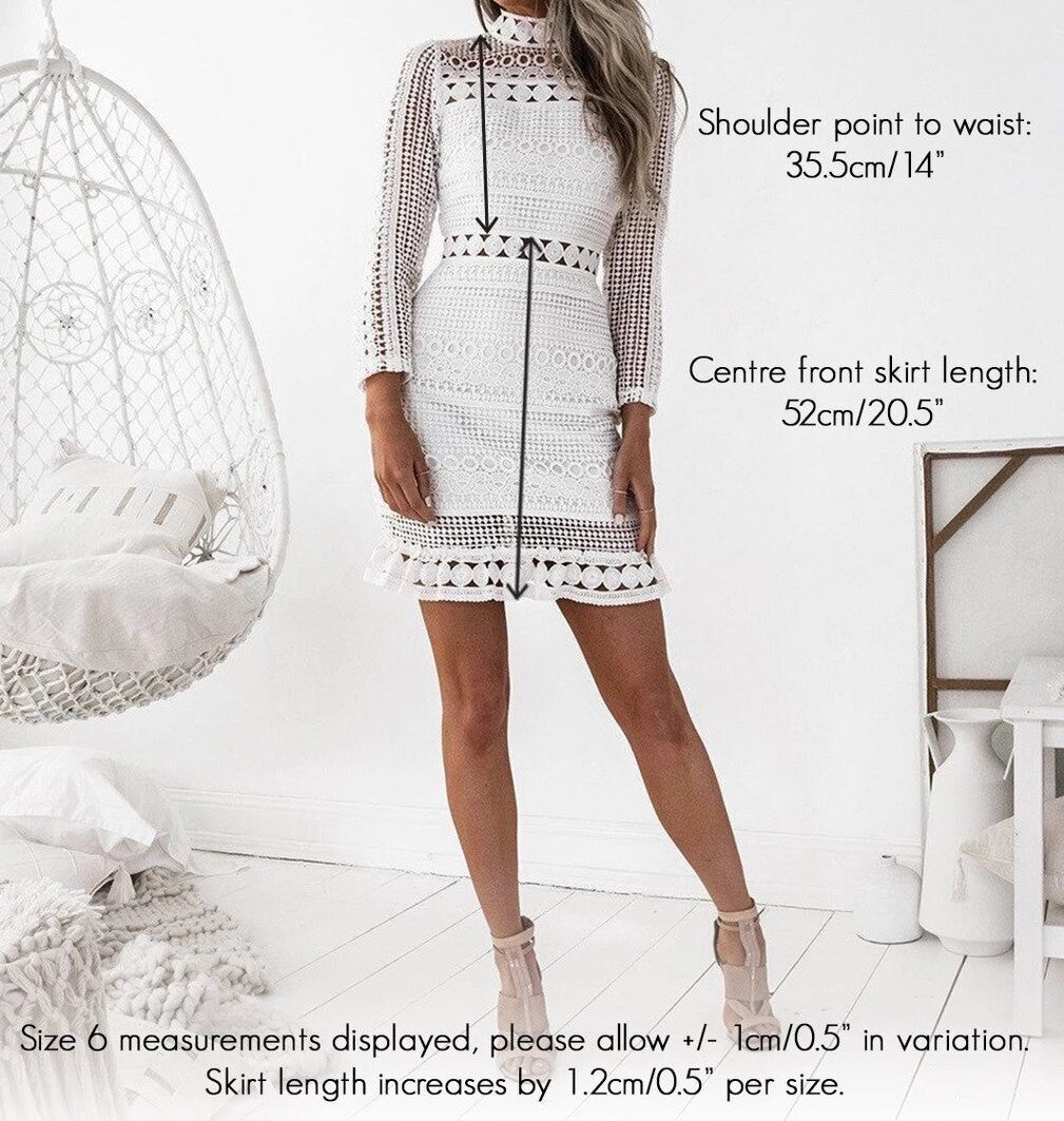 A woman stands wearing a white lace dress with a fitted silhouette. Measurements for shoulder point to waist and skirt length are annotated nearby. A hanging chair and decor enhance the light, airy environment.